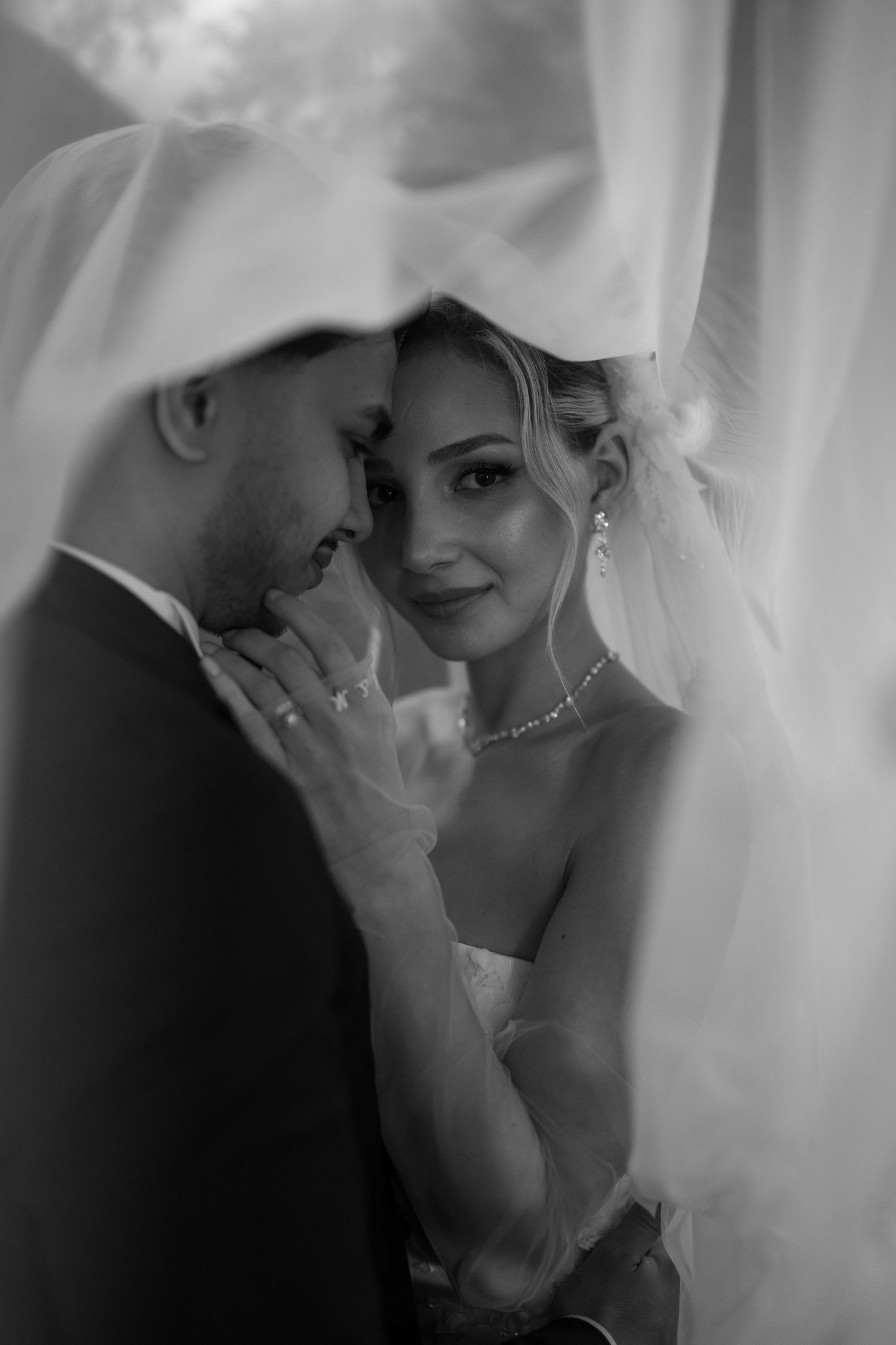 Intimate black and white wedding portraits showing tender moments through a delicate veil.