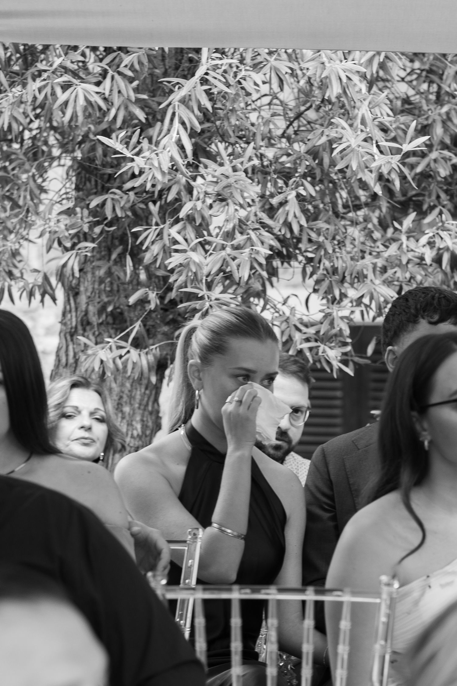 Black and white candid photo of emotional wedding guests during ceremony.