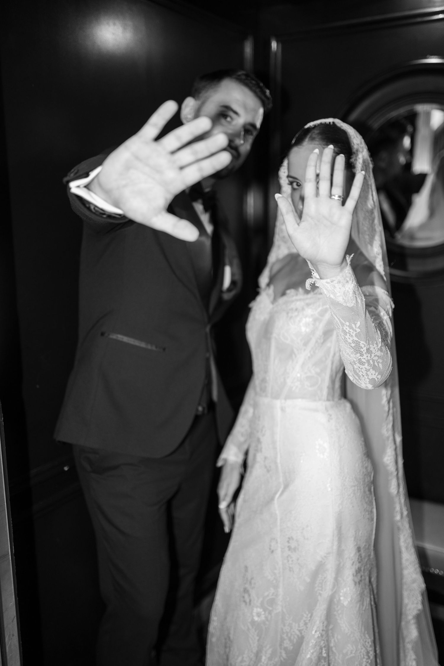 Black and white wedding photo with playful hand gestures showing wedding rings.
