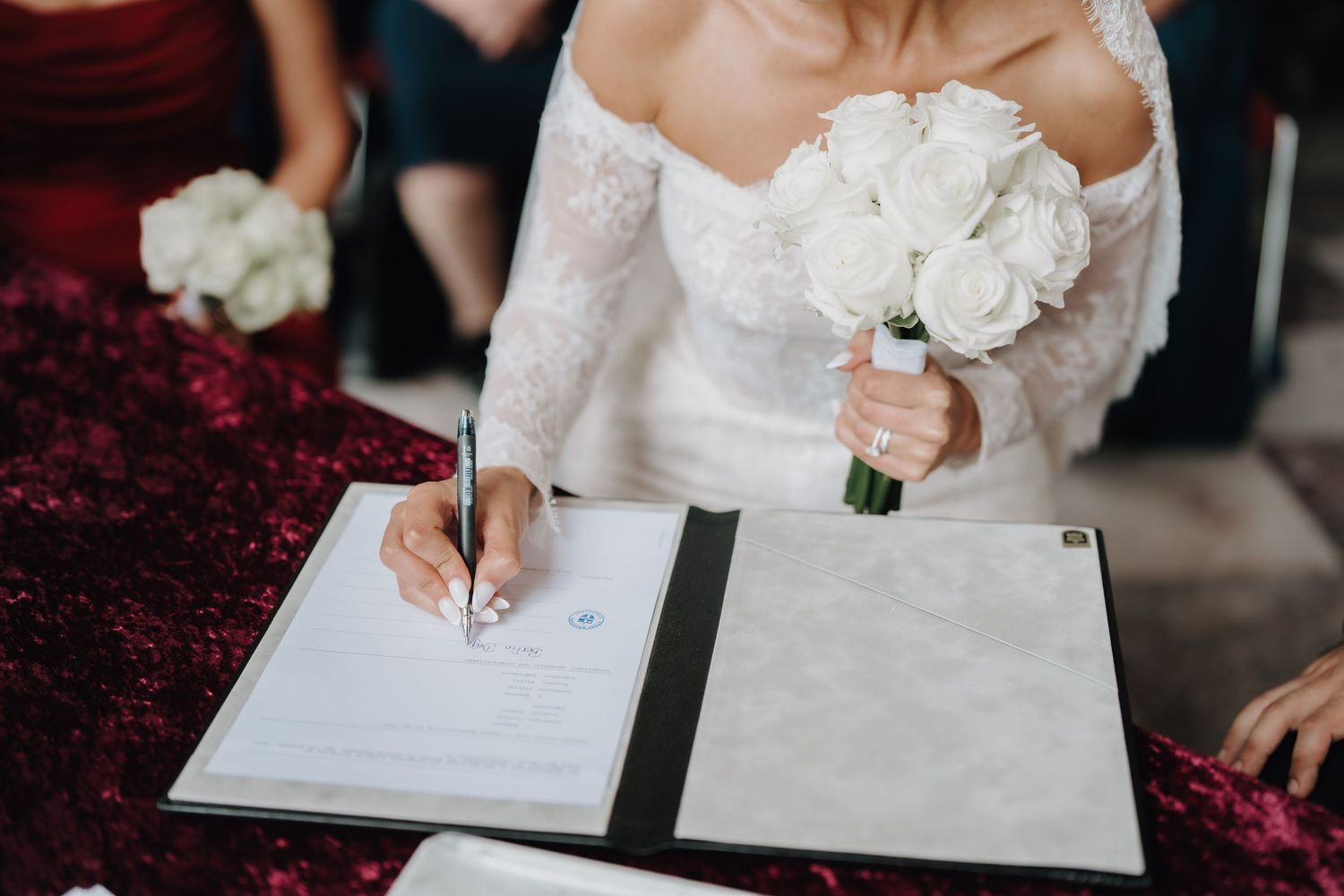 Close-up shots of newlyweds signing their marriage certificate.