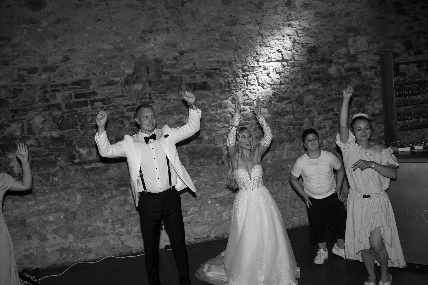 Wedding party dancing and celebrating in a rustic indoor reception venue.