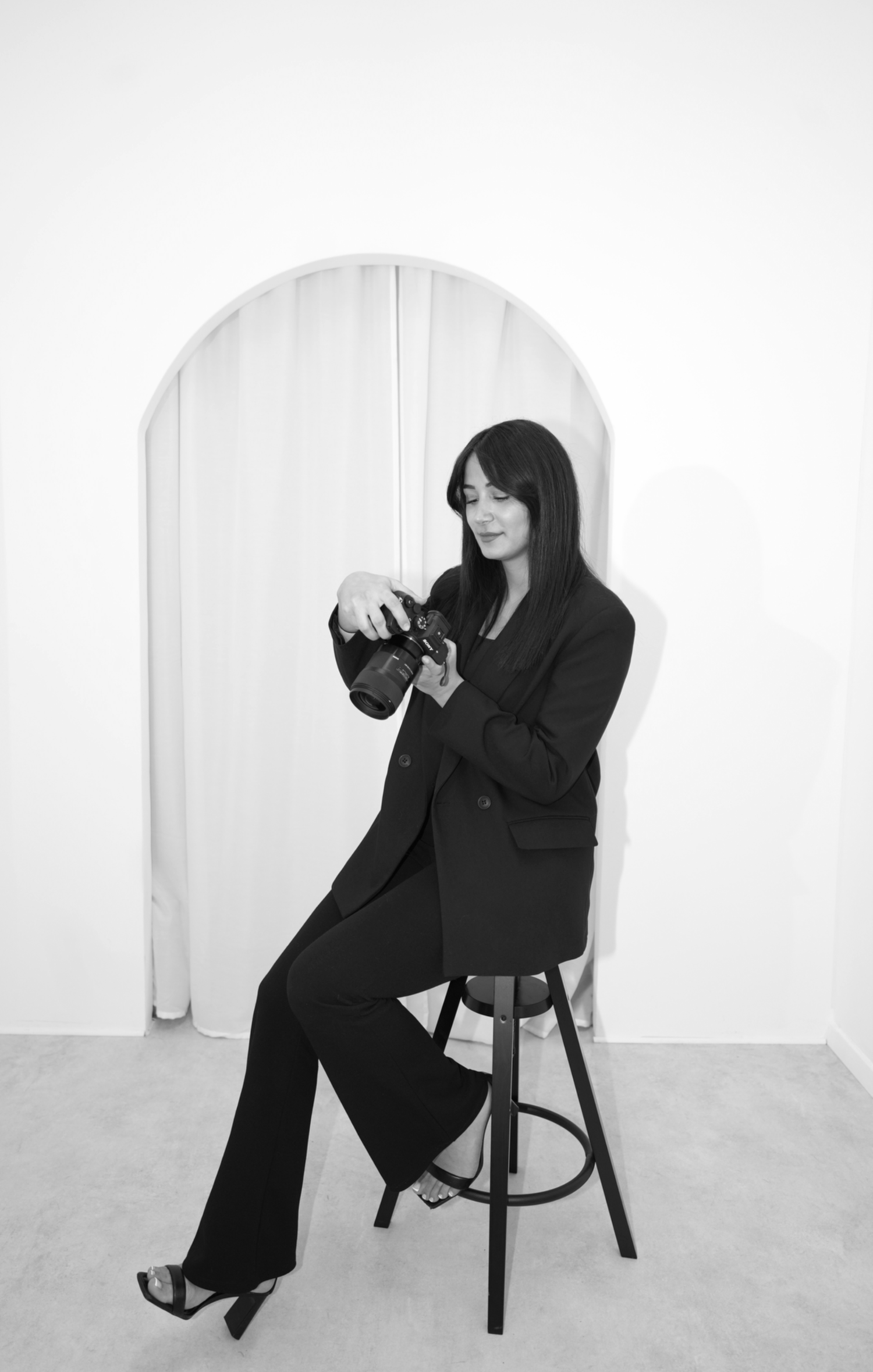 Artistic black and white portraits of a woman posing on a chair in professional attire.