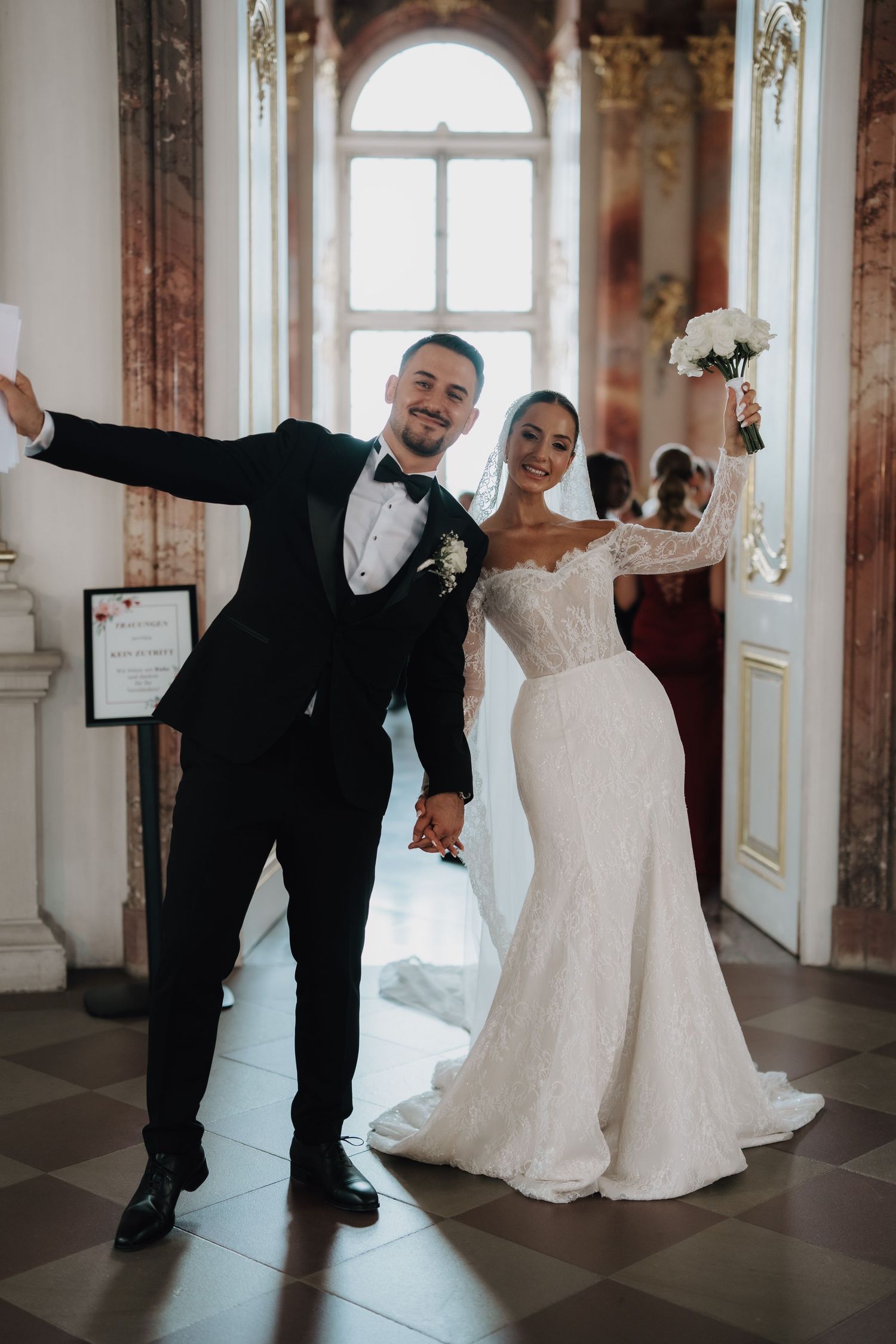 Playful wedding photos of newlyweds celebrating in an elegant marble hallway.