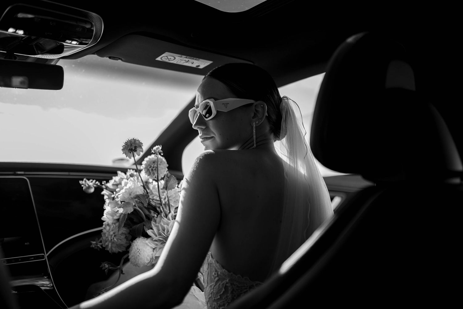 Dramatic black and white silhouettes captured inside a car on wedding day.