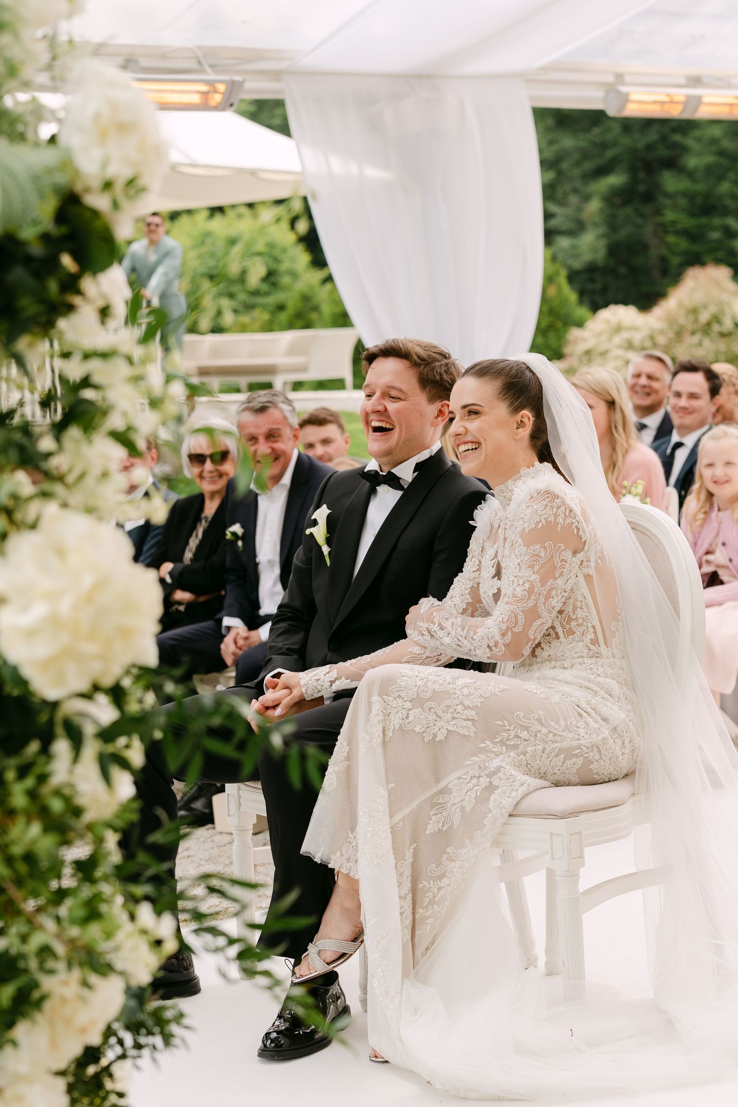 Wedding celebration under white tent with elegant decor and floral arrangements.
