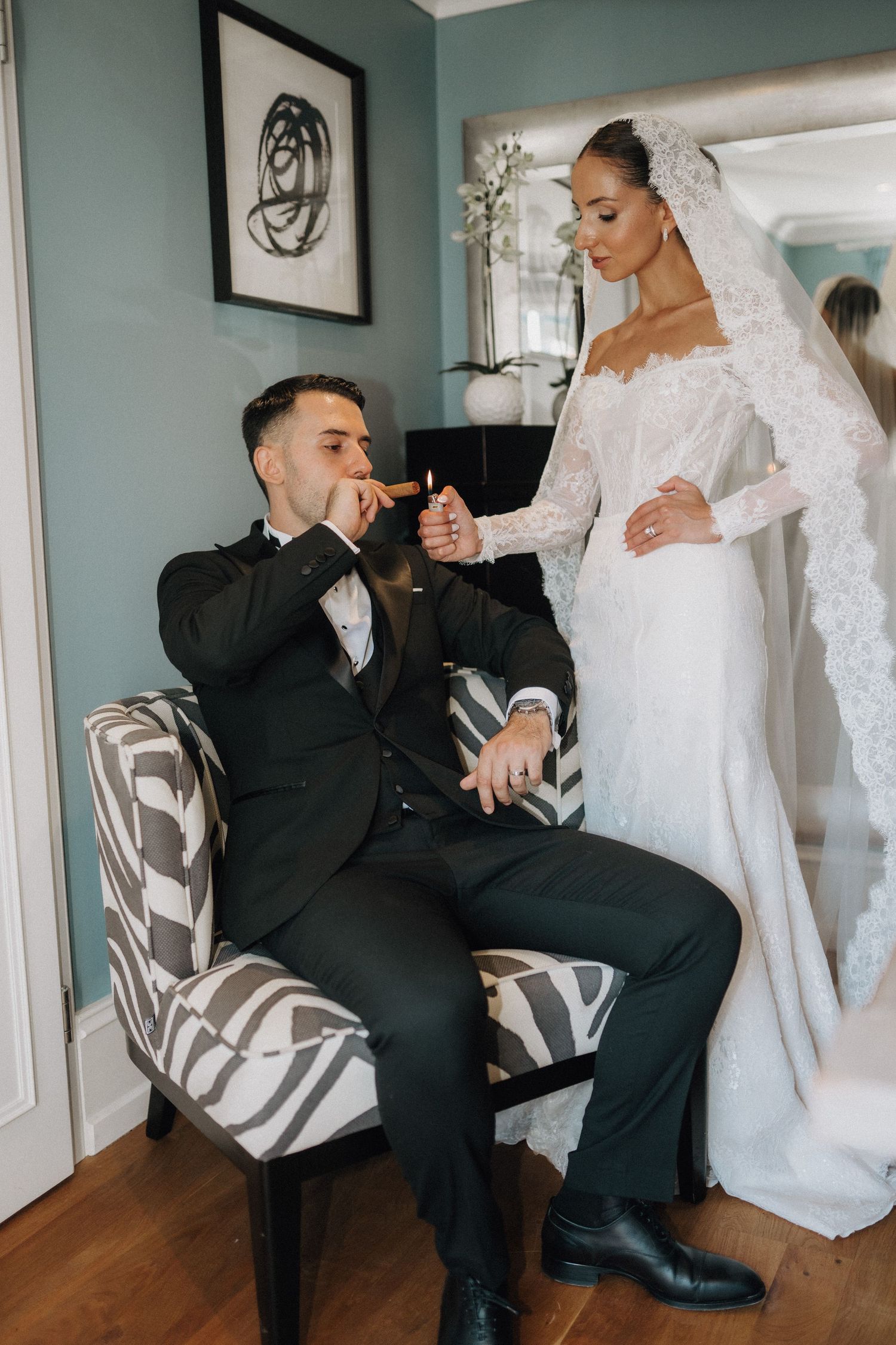 Wedding couple sharing a moment in a blue-walled room with zebra print chairs.