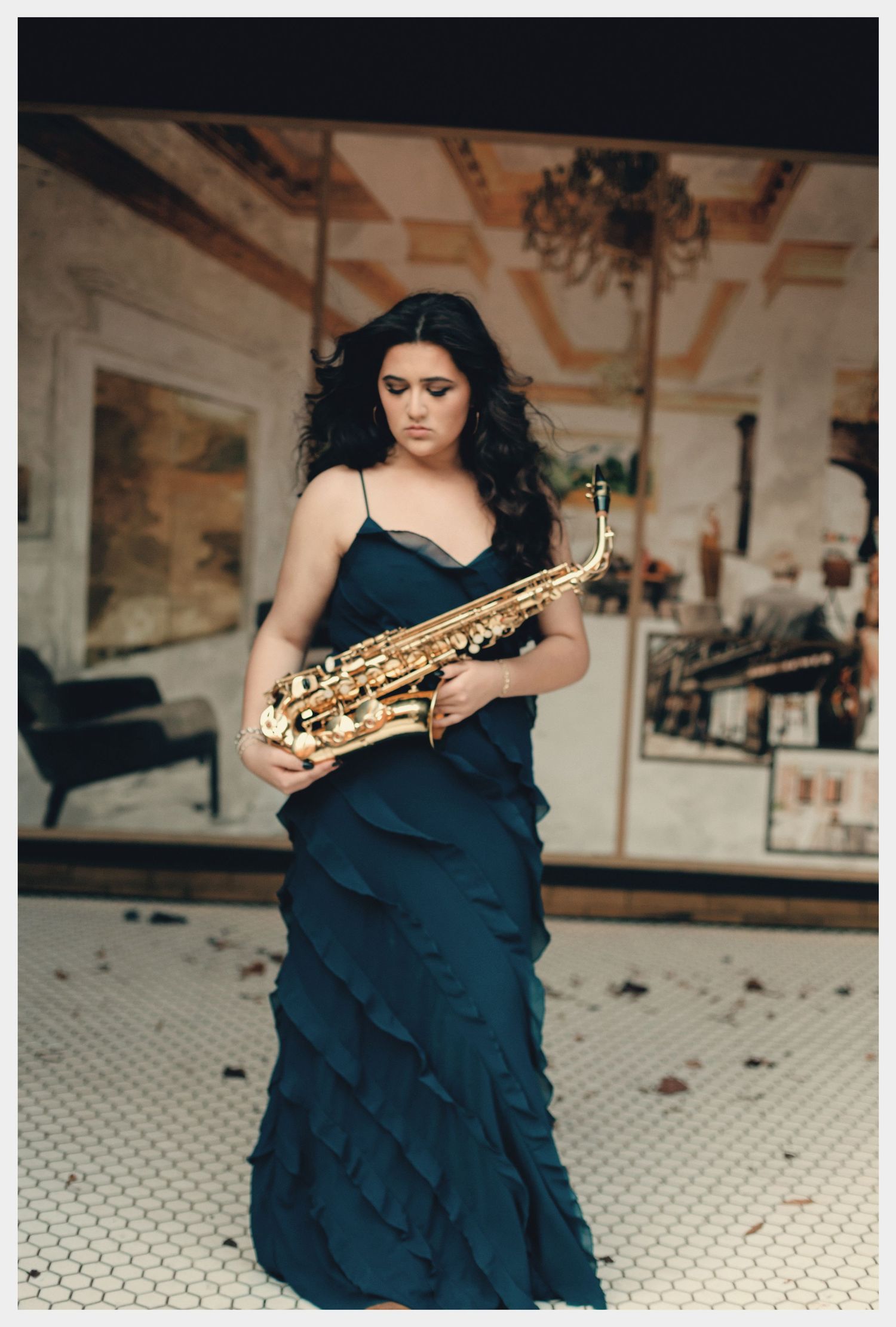 Woman in teal ruffled gown holding a gold saxophone in an elegant vintage interior setting.