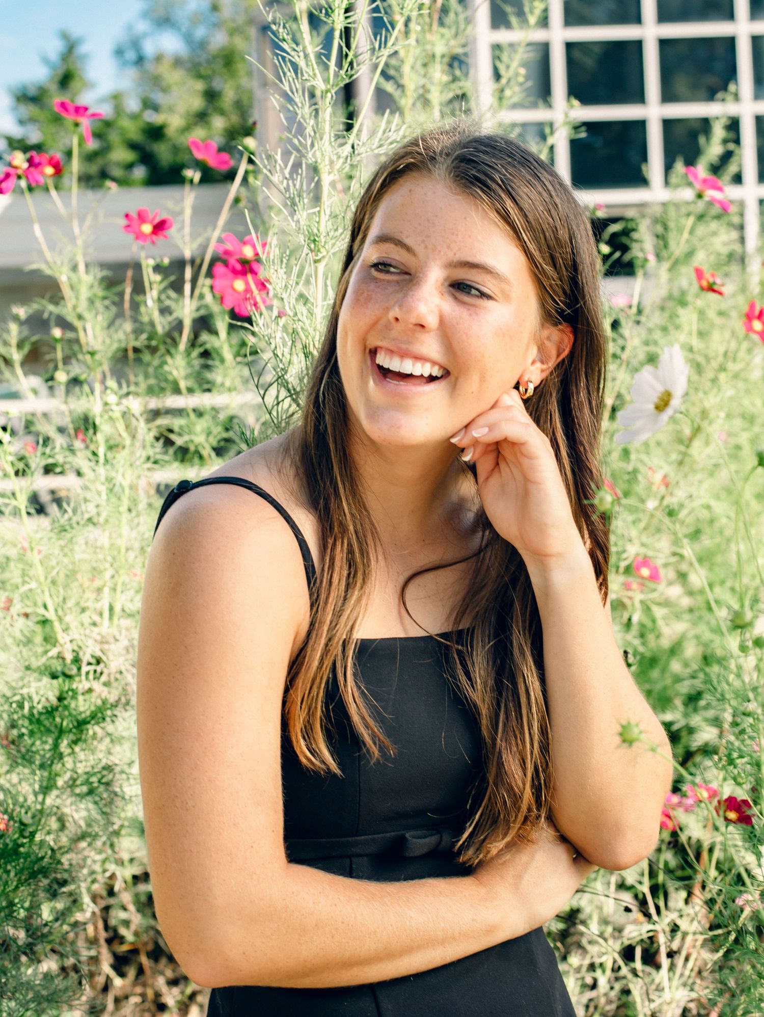 High school senior girl laughing in florals wearing a black dress.