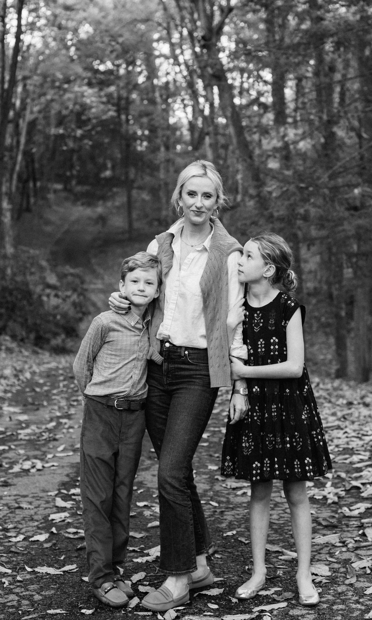 Blonde Mother with son and daughter posing in the fall leaves photographed in black and white.