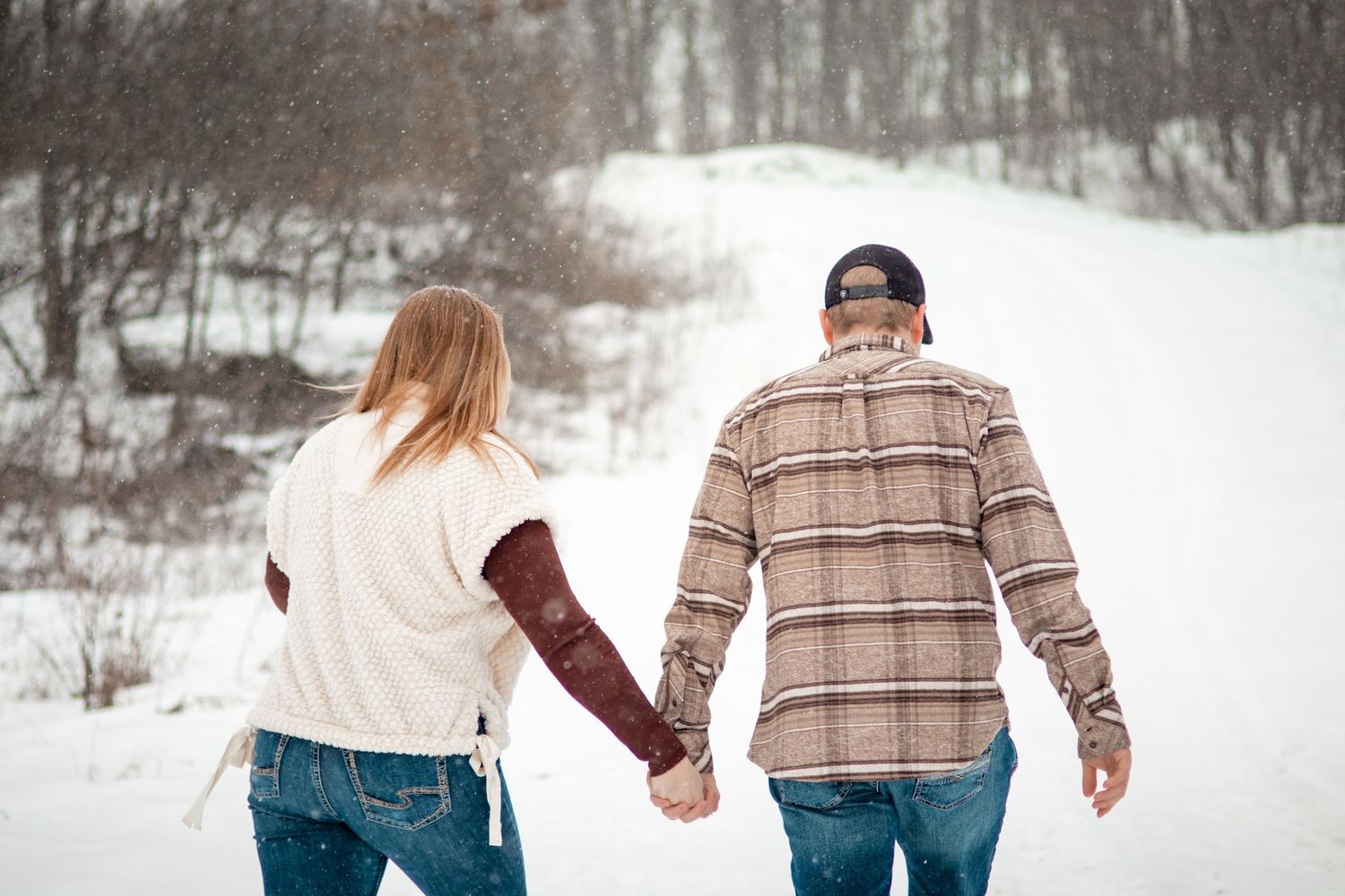 Couple in casual winter clothing walking together in snowy field.