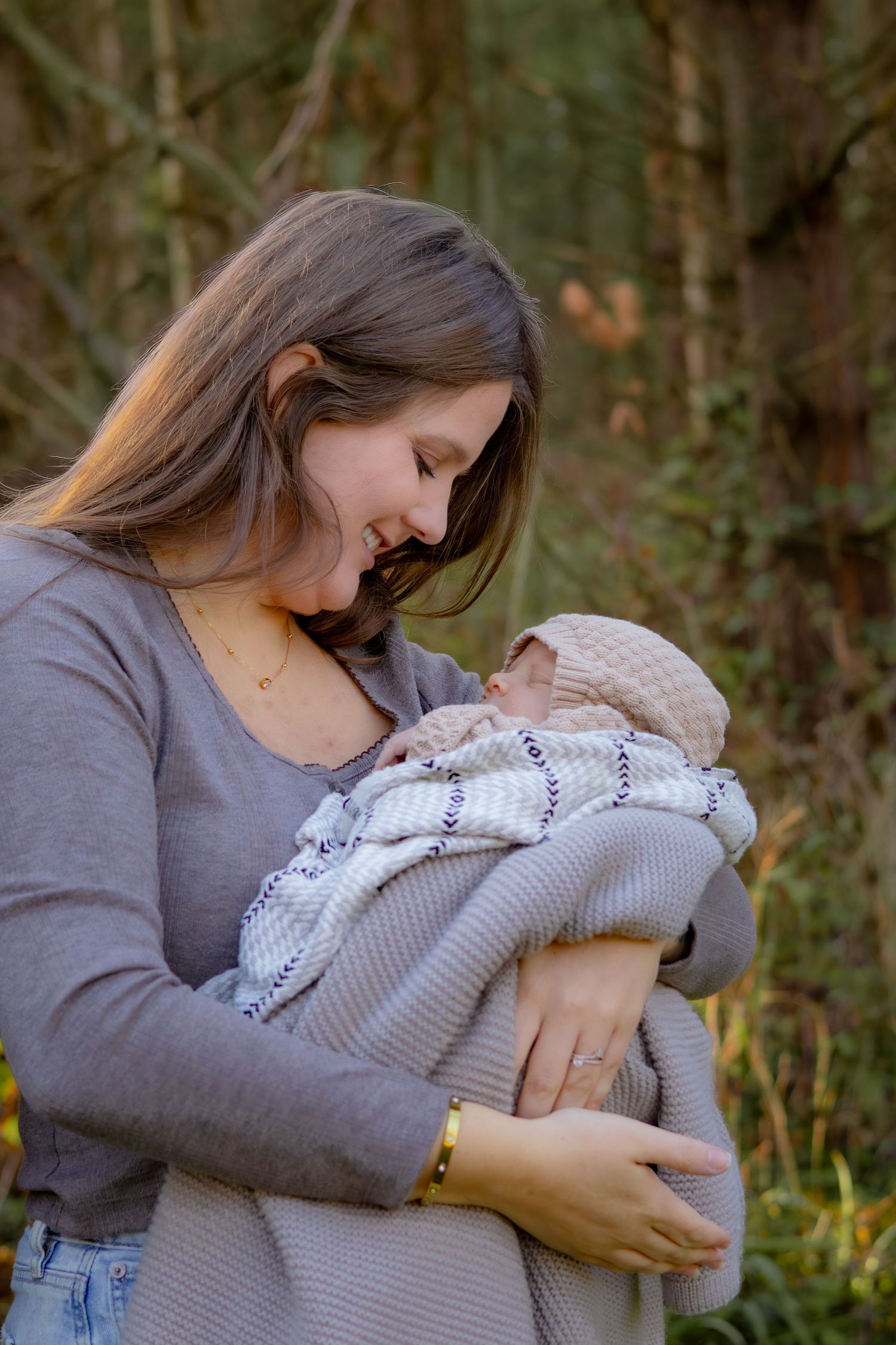 A tender moment between parent and baby wrapped in a knit blanket outdoors.
