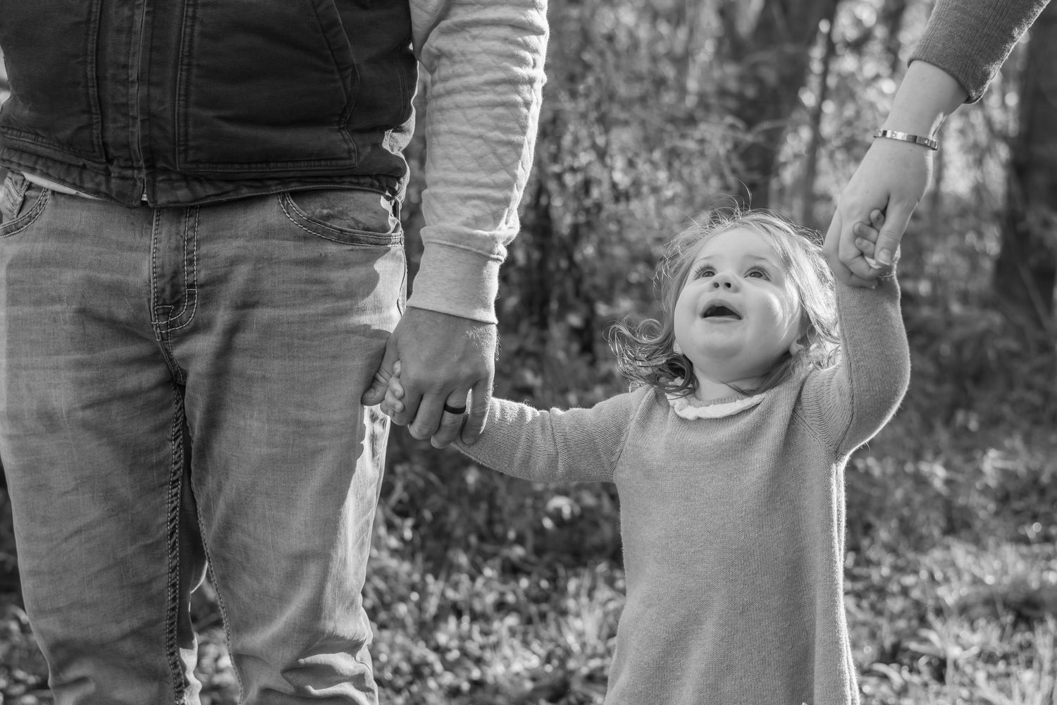 Black and white portrait of family members laughing together outdoors.