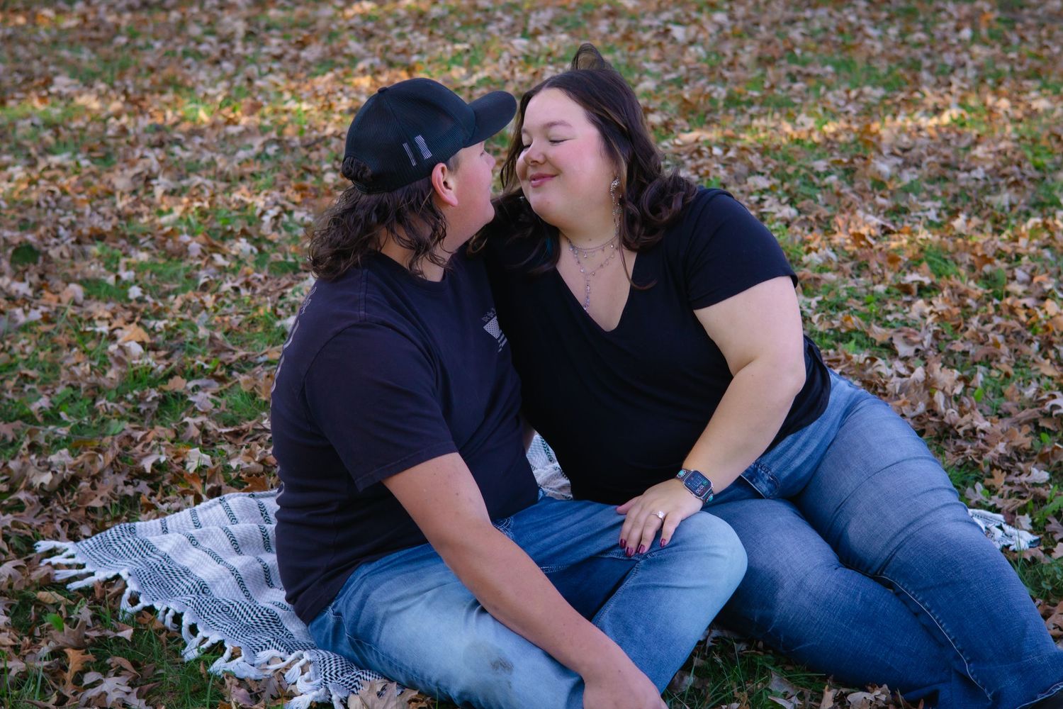 Intimate couples photo session with people sitting together on autumn leaves.