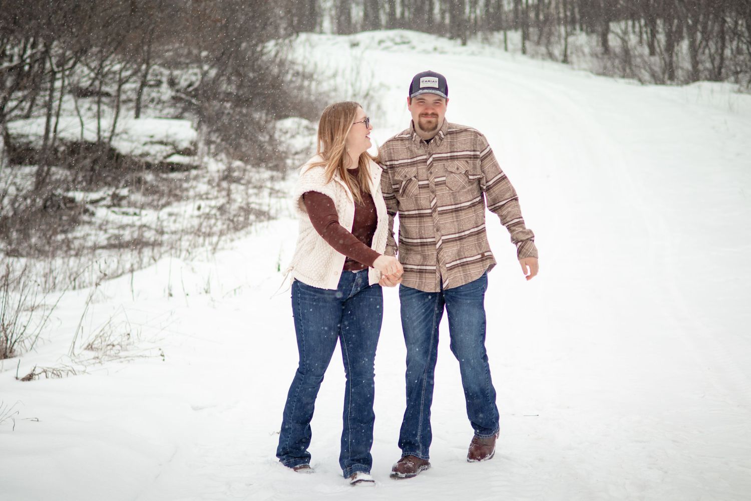 A couple walking together through a snow-covered winter landscape.
