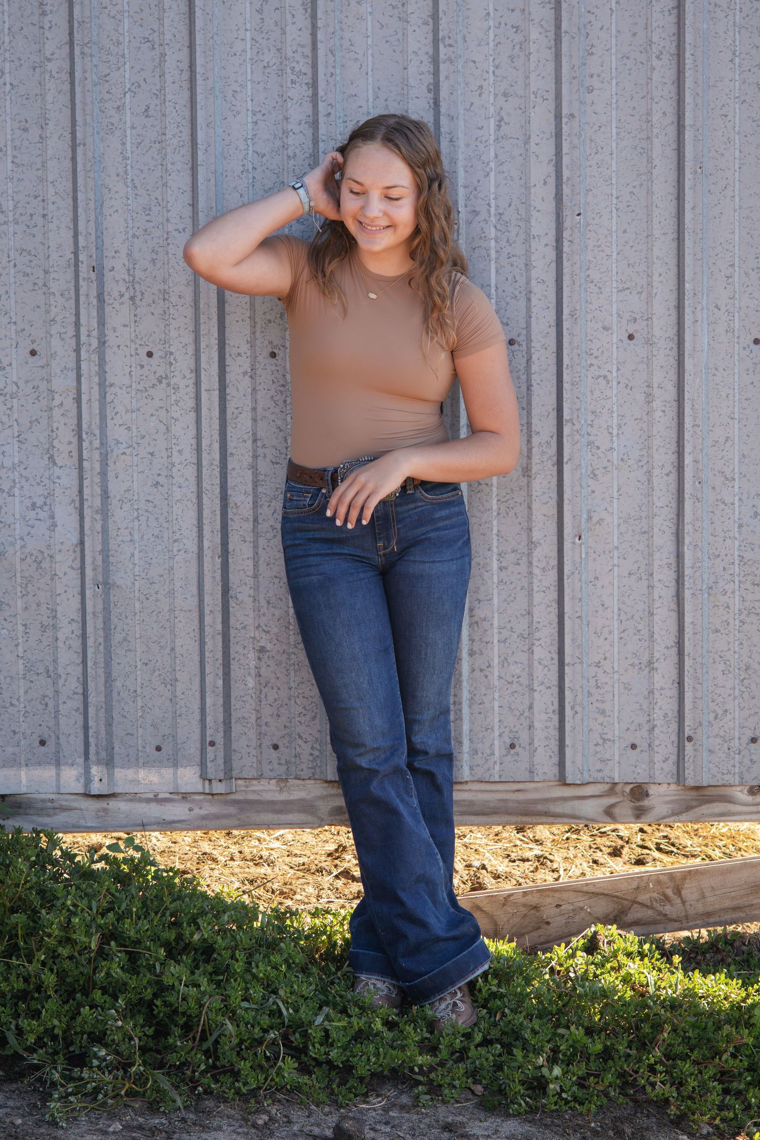 Casual outdoor portrait series against a gray wall with greenery and natural lighting.