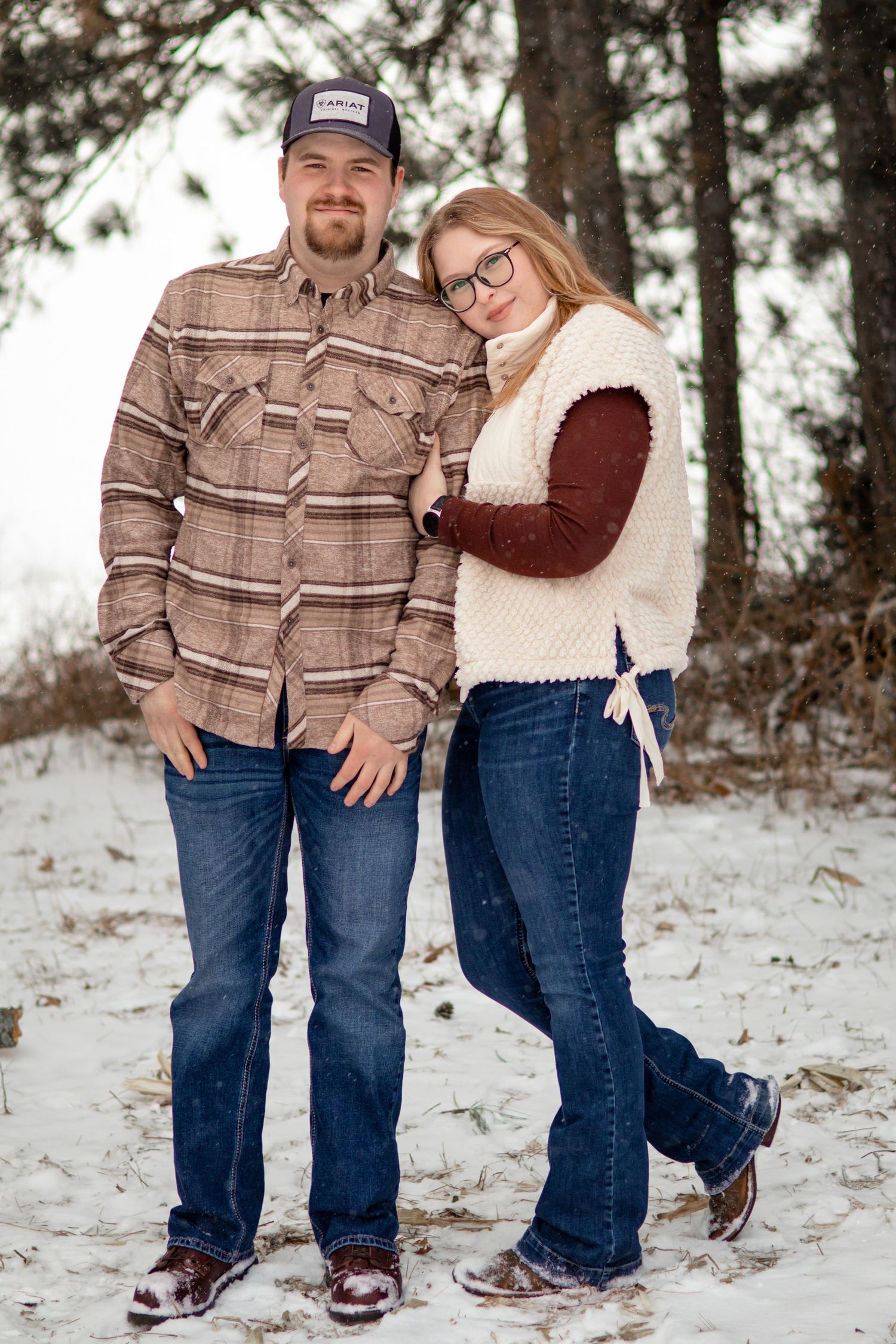 Winter engagement photos showing couple in plaid and casual wear on snowy ground.