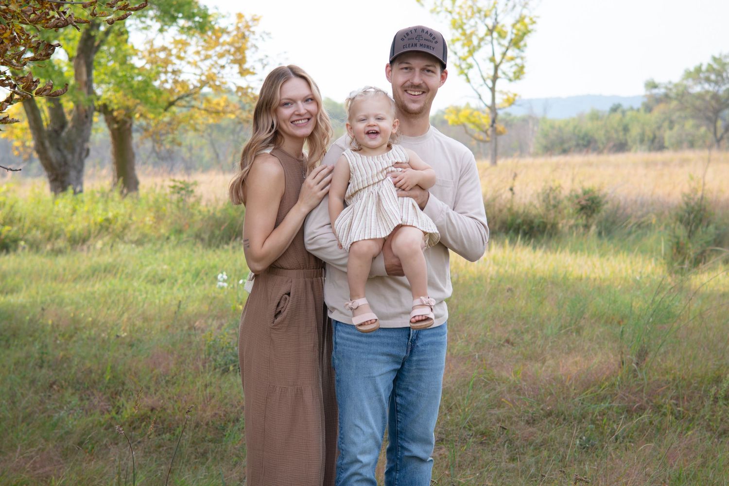 Family portrait session in a golden field during fall season.