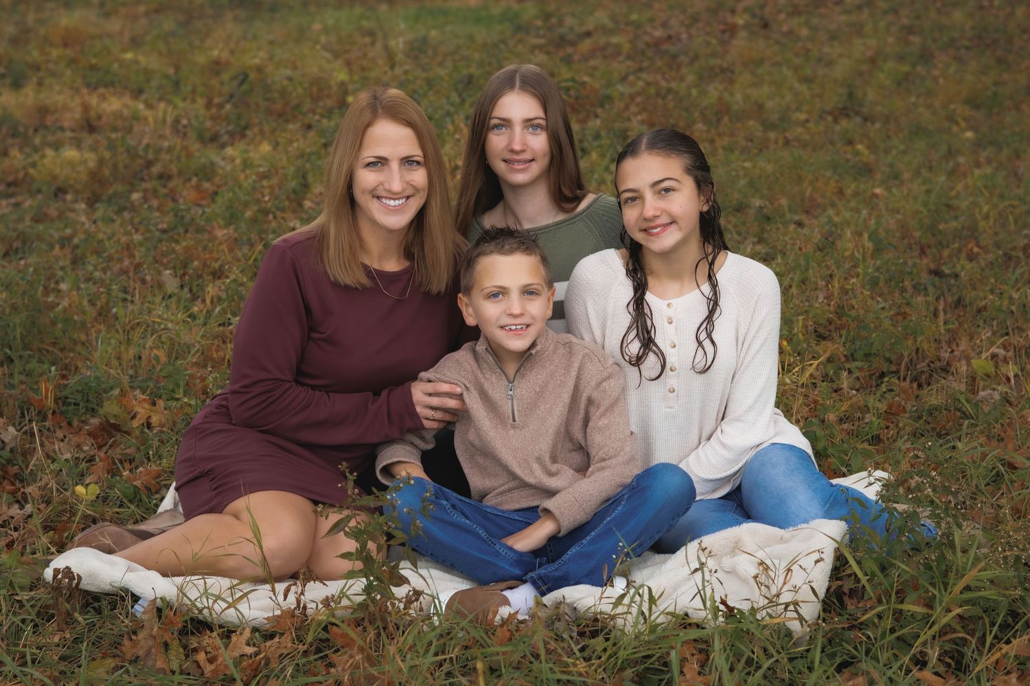 People sitting together on grass having casual portraits taken outdoors.