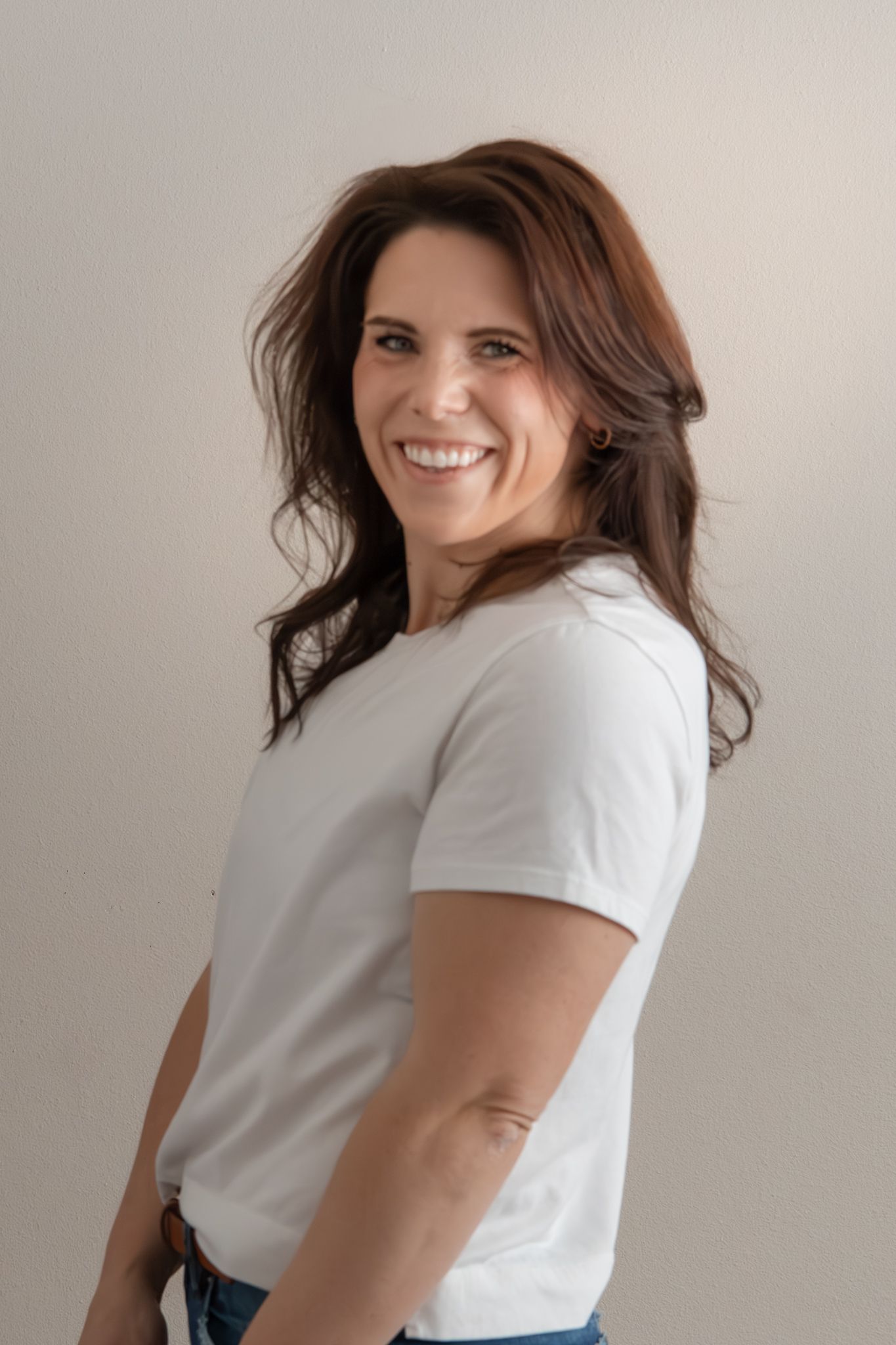 Fashion portraits in white t-shirt and jeans against minimalist studio setting.