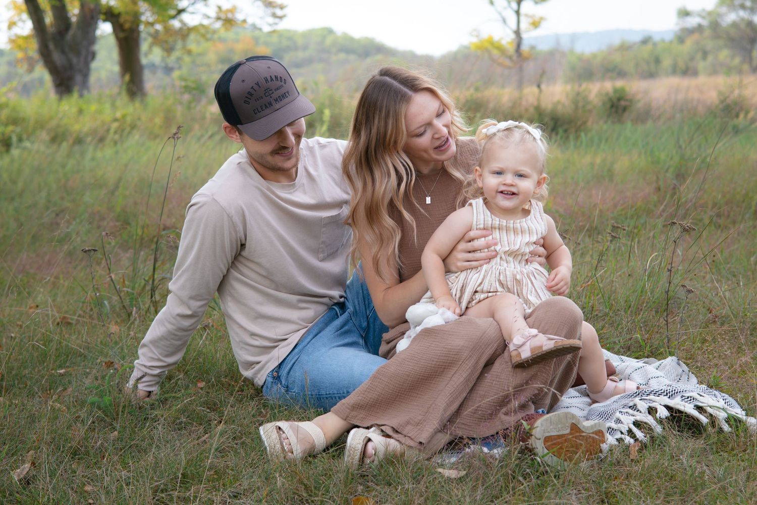 Family relaxing together on blanket during outdoor photo session in golden light.