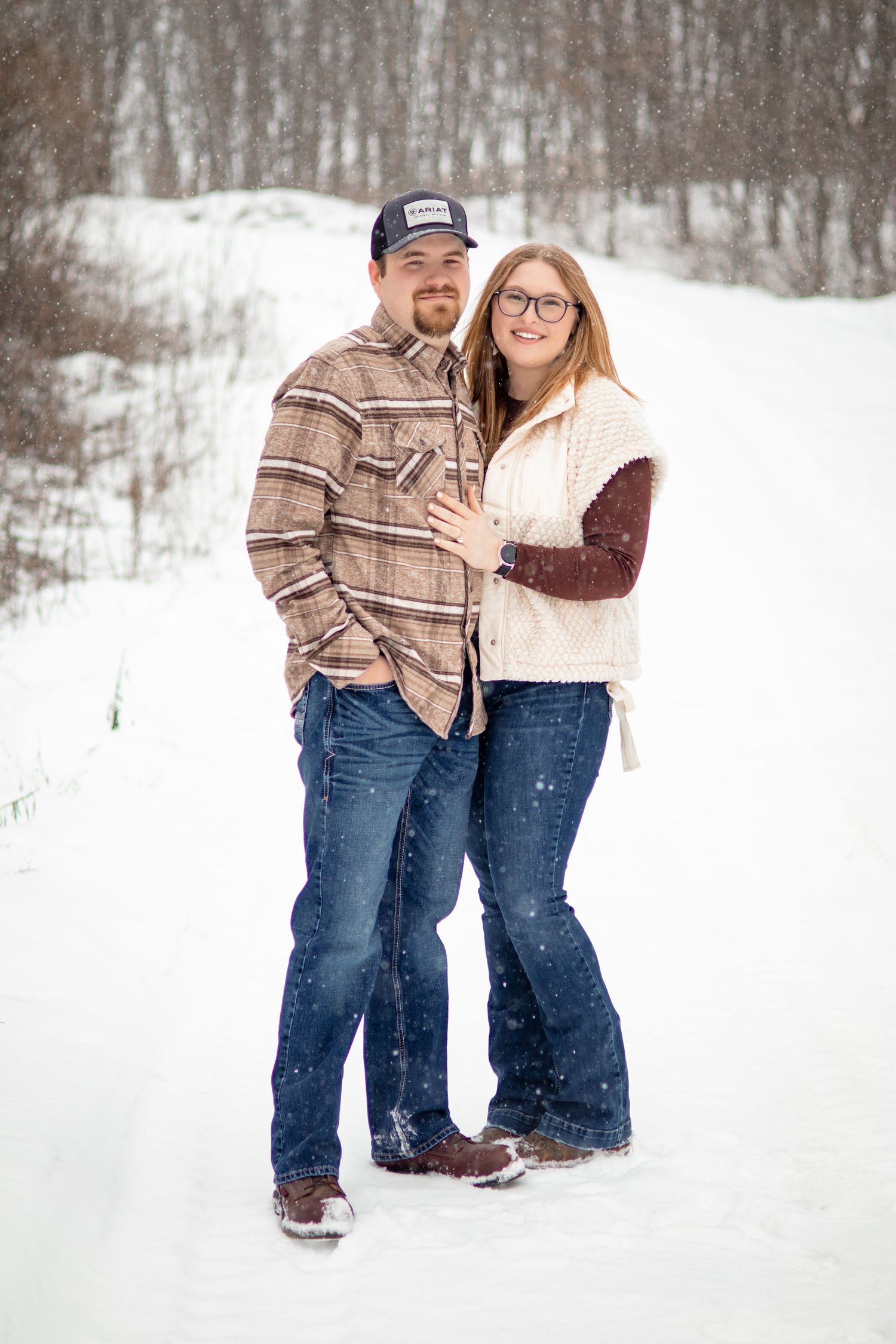 A couple shares a joyful moment in the snow during their engagement session.