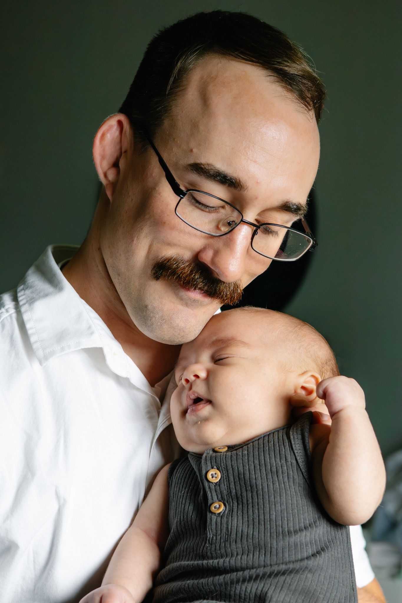 Intimate moment between parent and sleeping infant in casual setting.