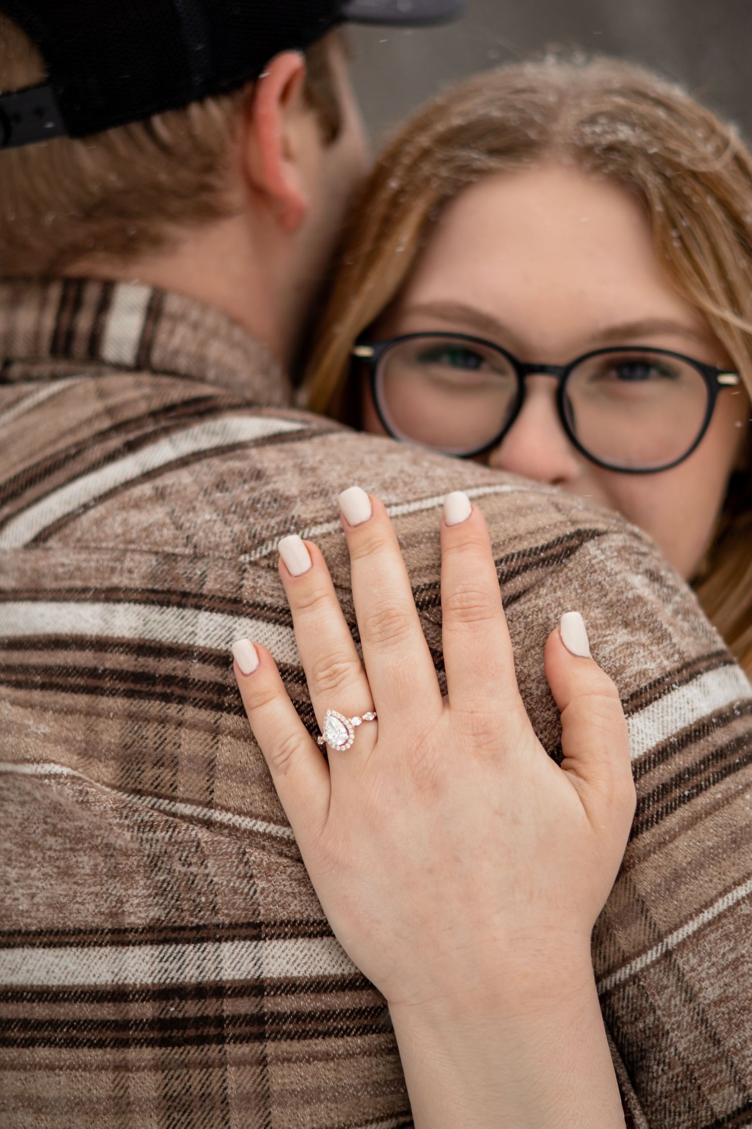 Close-up detail of an engagement ring on a plaid jacket.