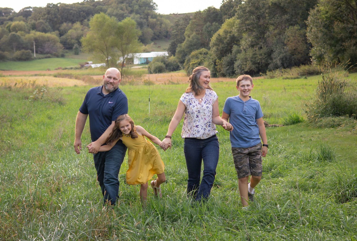 Group walking together through a scenic meadow during golden hour photography session.