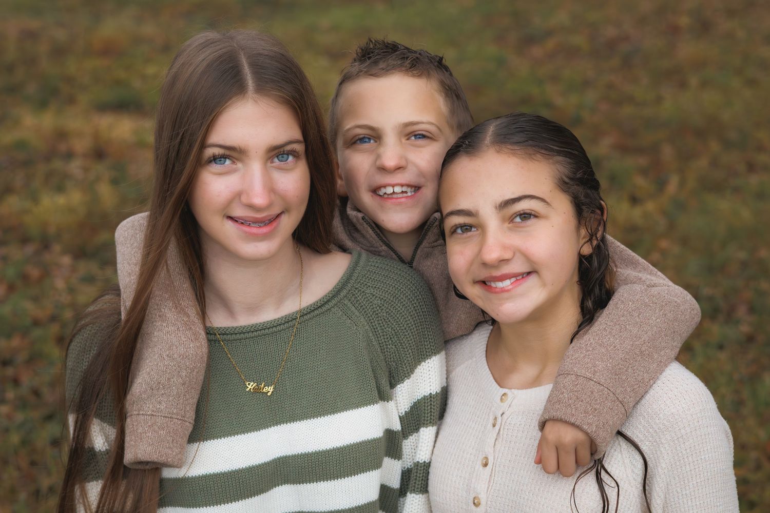 Group portrait session outdoors with people wearing coordinated neutral and green tones.
