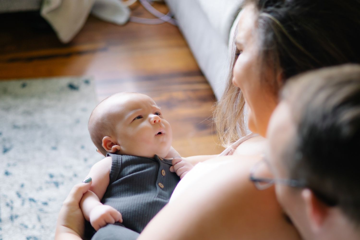 Sweet moment between caregiver and infant on patterned rug indoors.