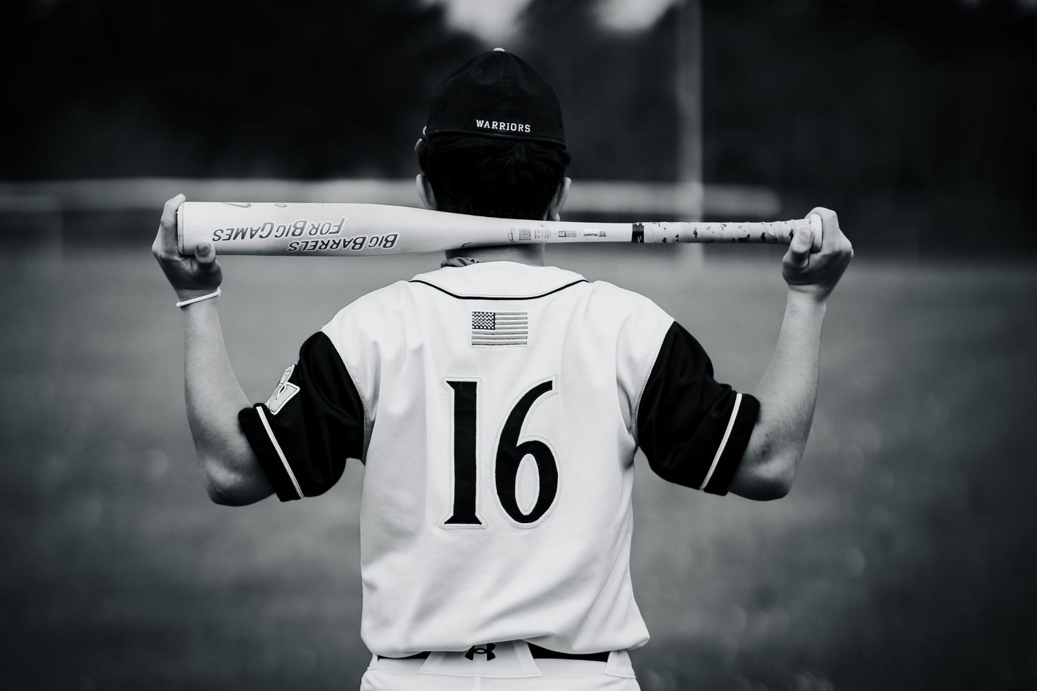 Black and white photo of baseball player holding bat behind shoulders showing number 16 jersey on field.
