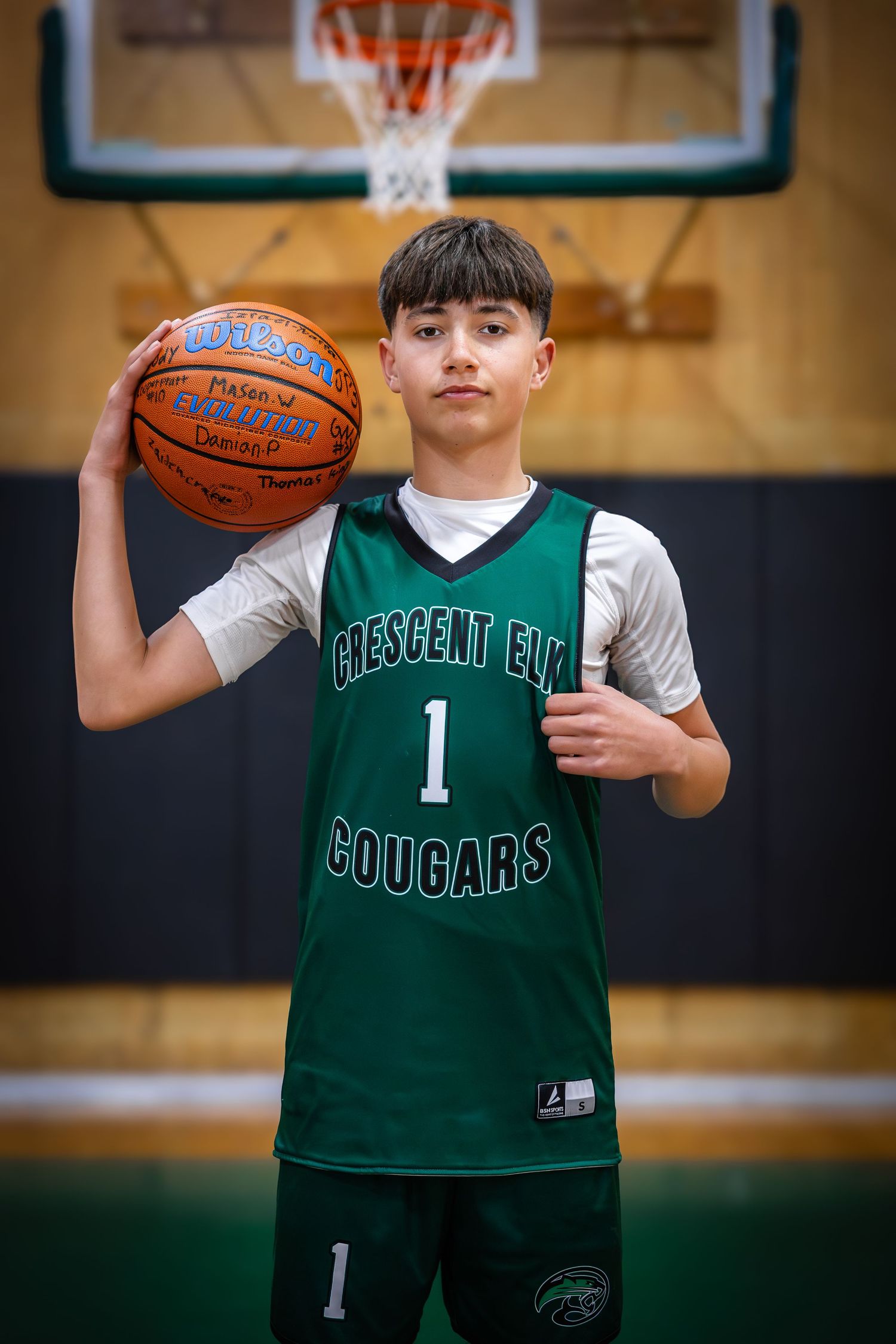 Young basketball player in Crescent Elm Cougars jersey number 1 holding Wilson ball in gym.