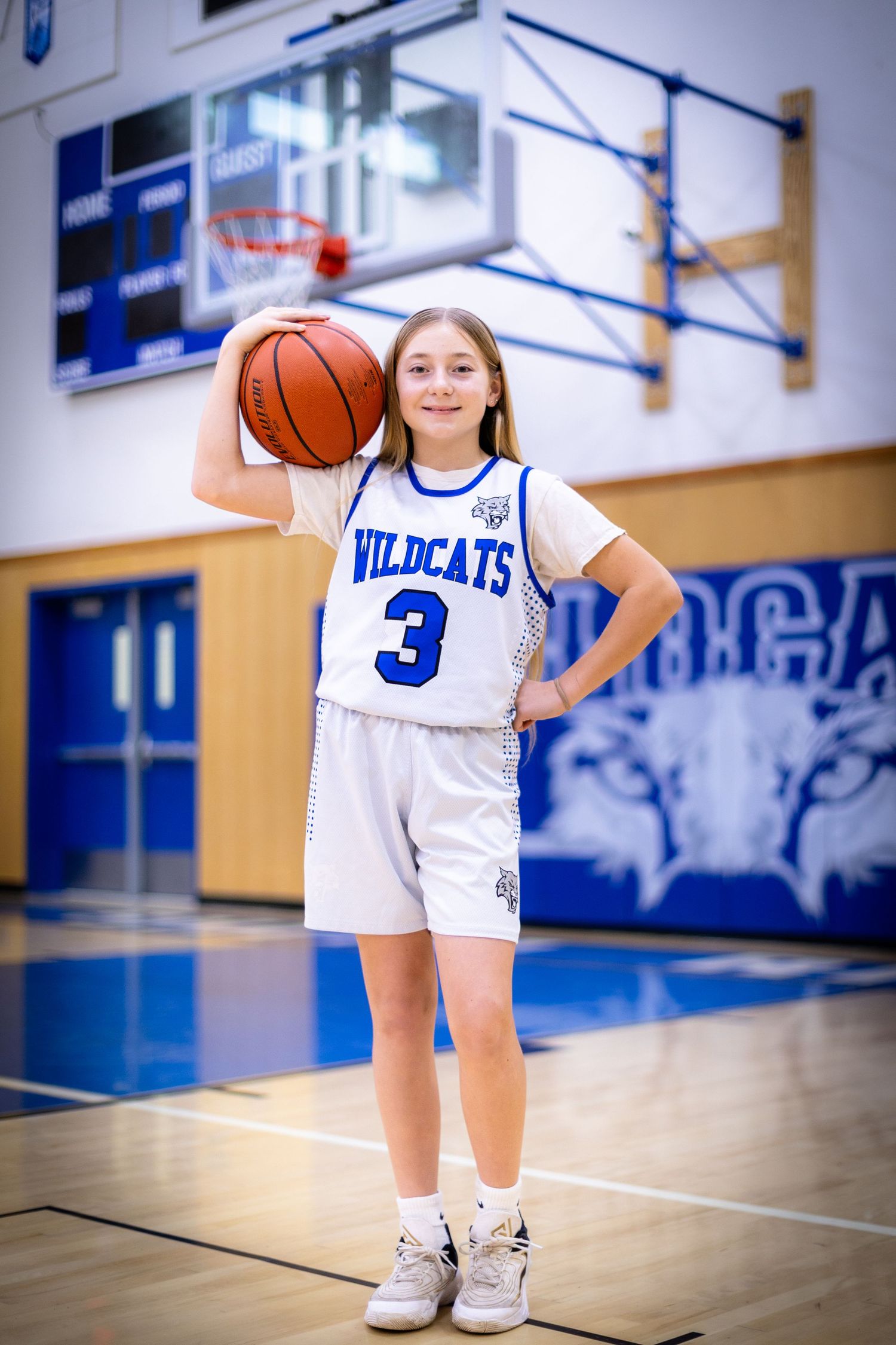 A Wildcats basketball player wearing jersey number 3 poses with a ball in a blue gym.