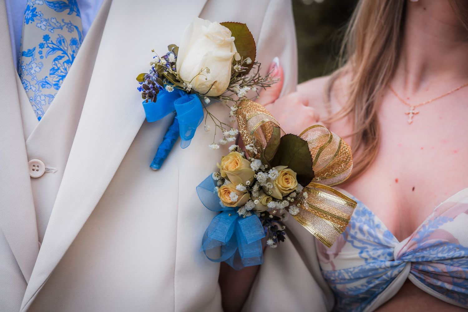 Close-up of matching prom corsage and boutonniere with blue ribbon and white roses.