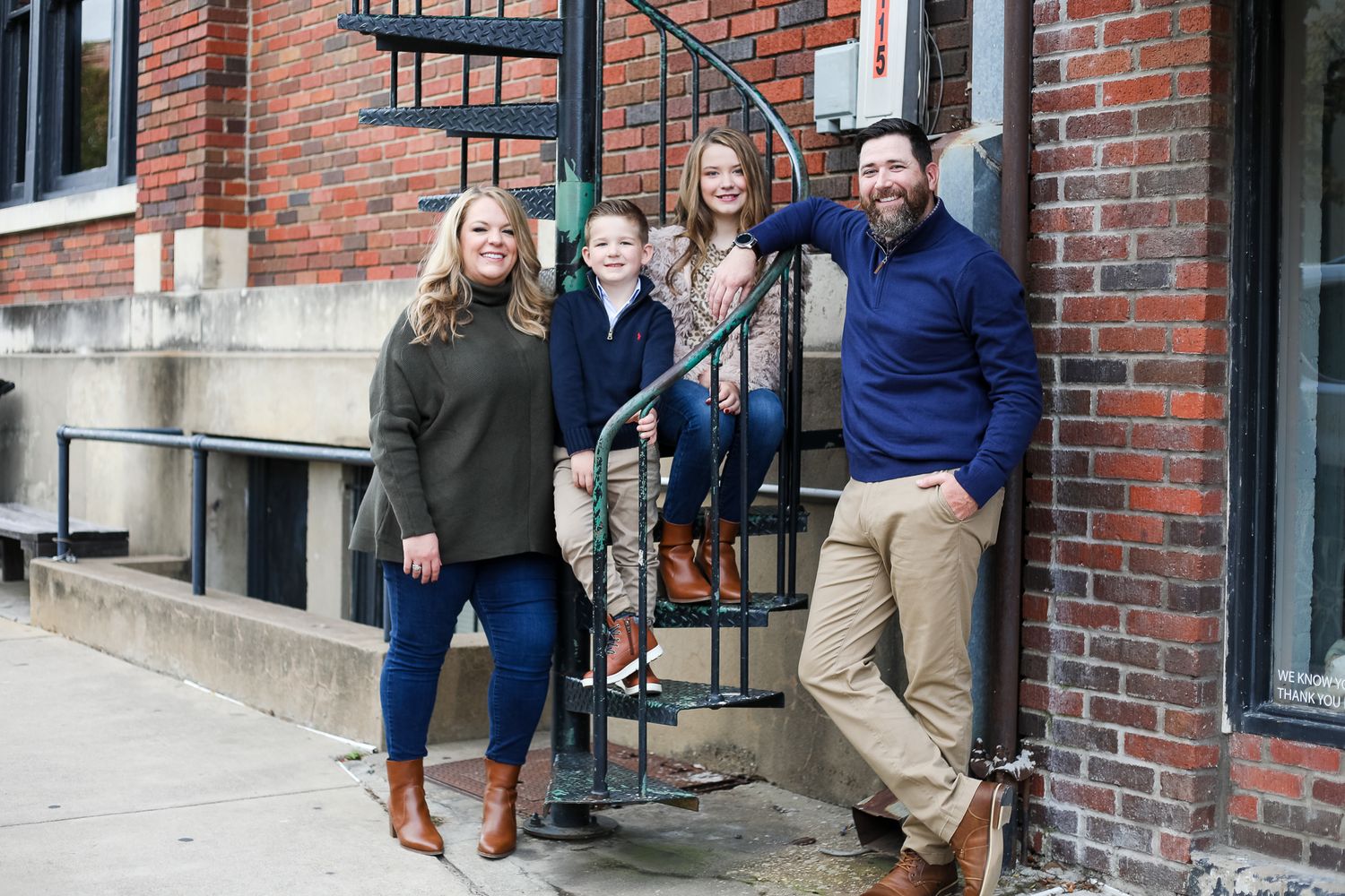 A group stands together on brick steps outside a building entrance in casual fall attire.