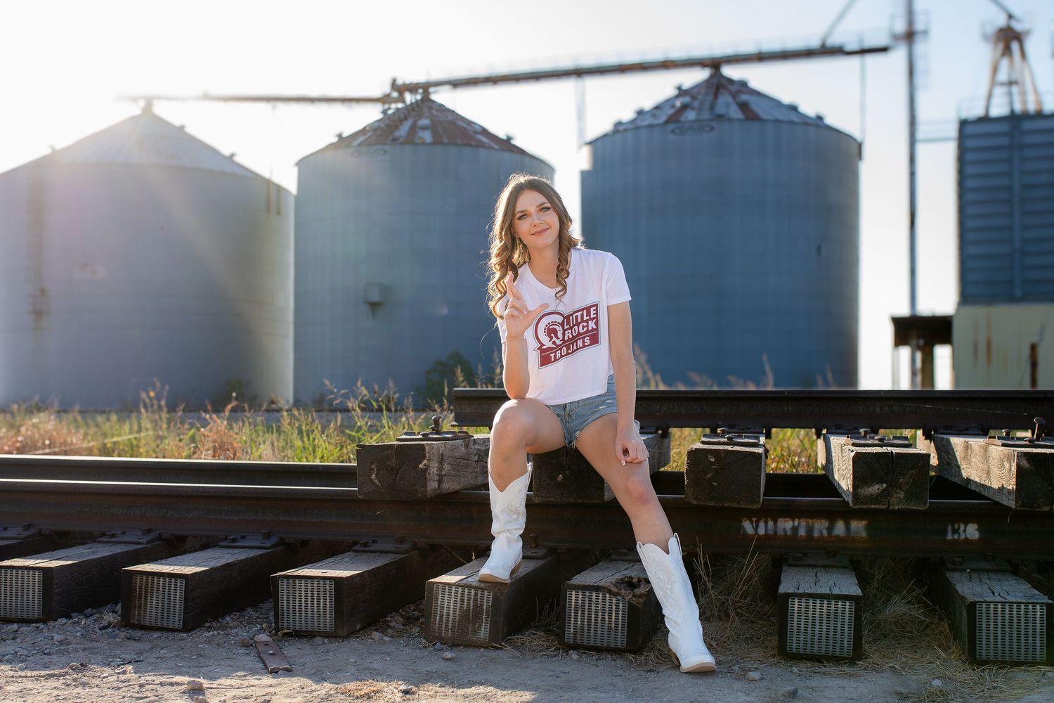A casual lifestyle photoshoot at sunset with grain silos in the background and railroad tracks in the foreground.