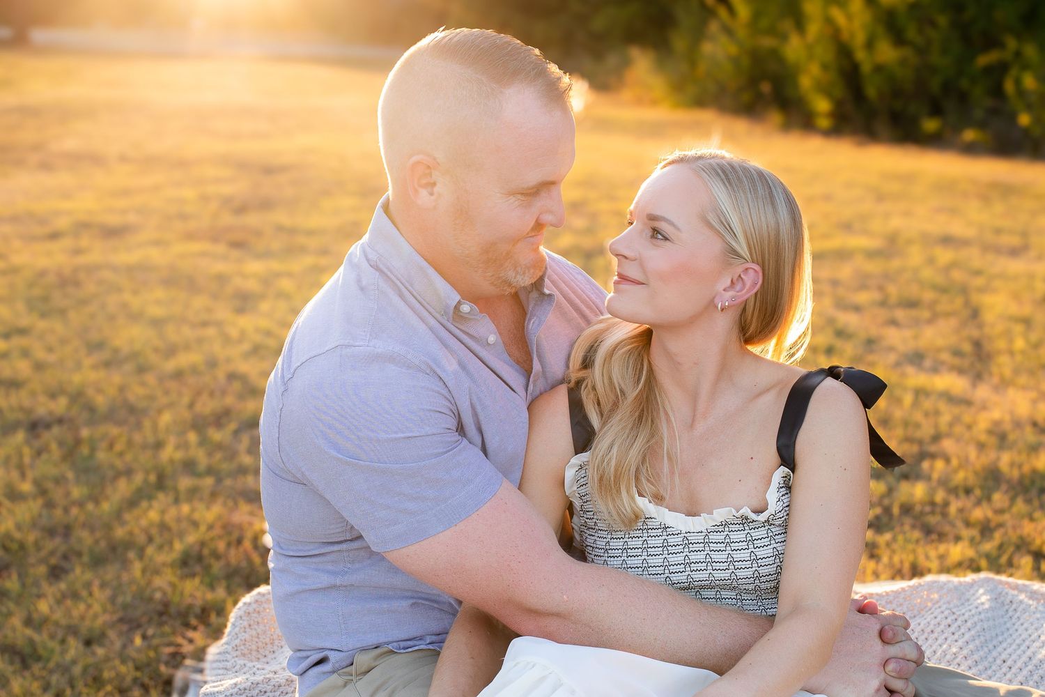 A couple shares tender moments during a romantic golden hour photoshoot in a sun-lit outdoor setting.