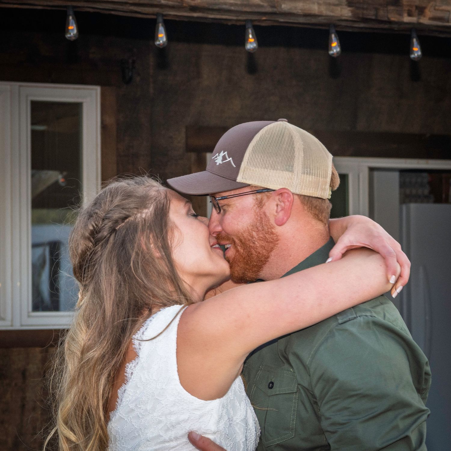 The bride and groom embracing and kissing while dancing at their wedding reception.