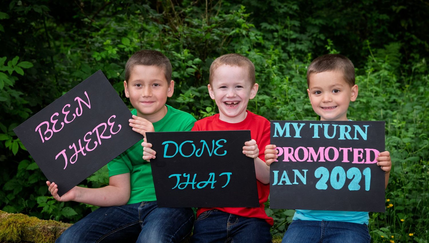Fun sibling baby announcement portrait with three boys holding signs reading been there, done that, my turn promoted Jan 2021.
