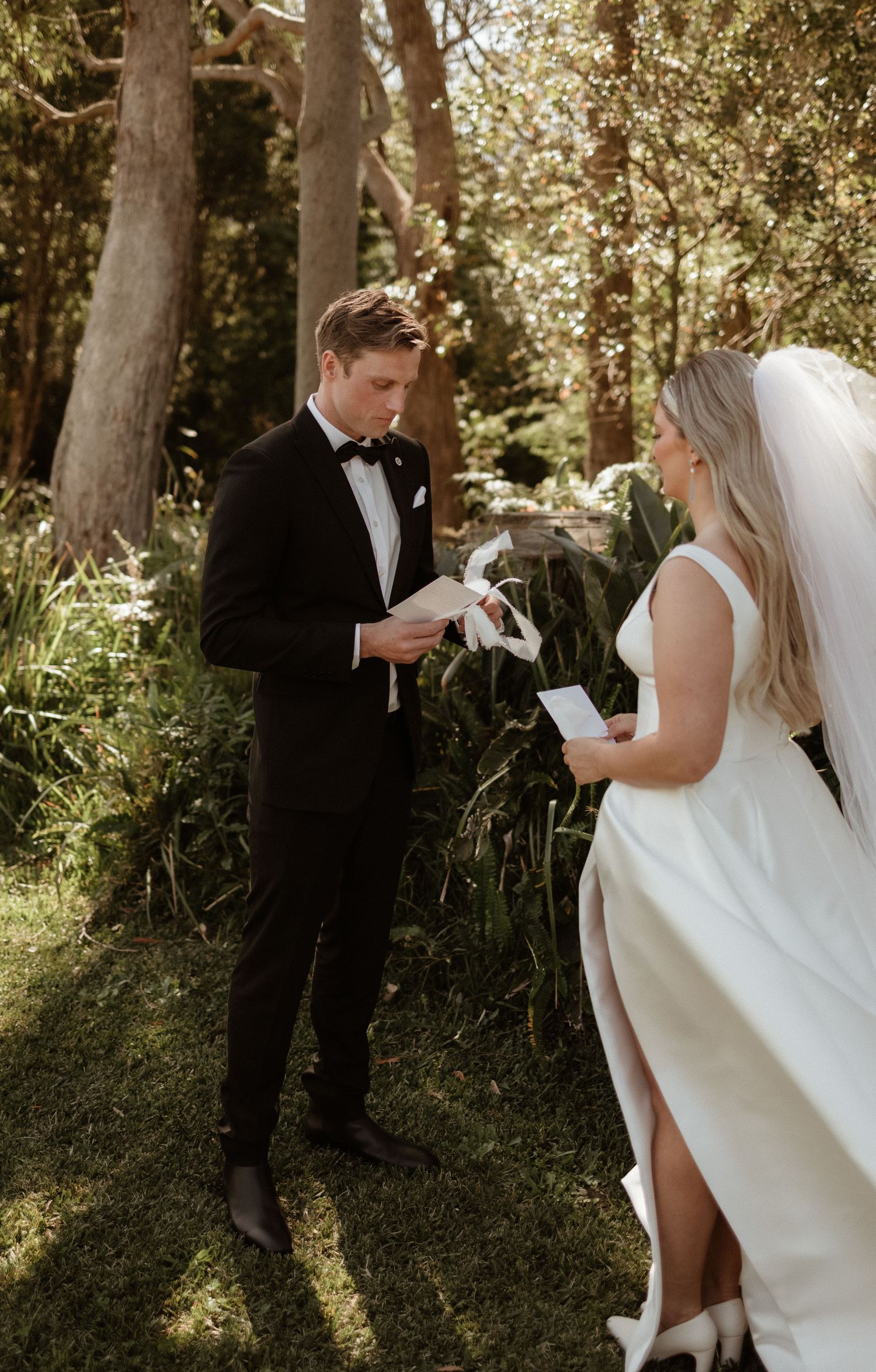 Groom reading wedding vows to his bride in a lush green garden during an intimate first look.