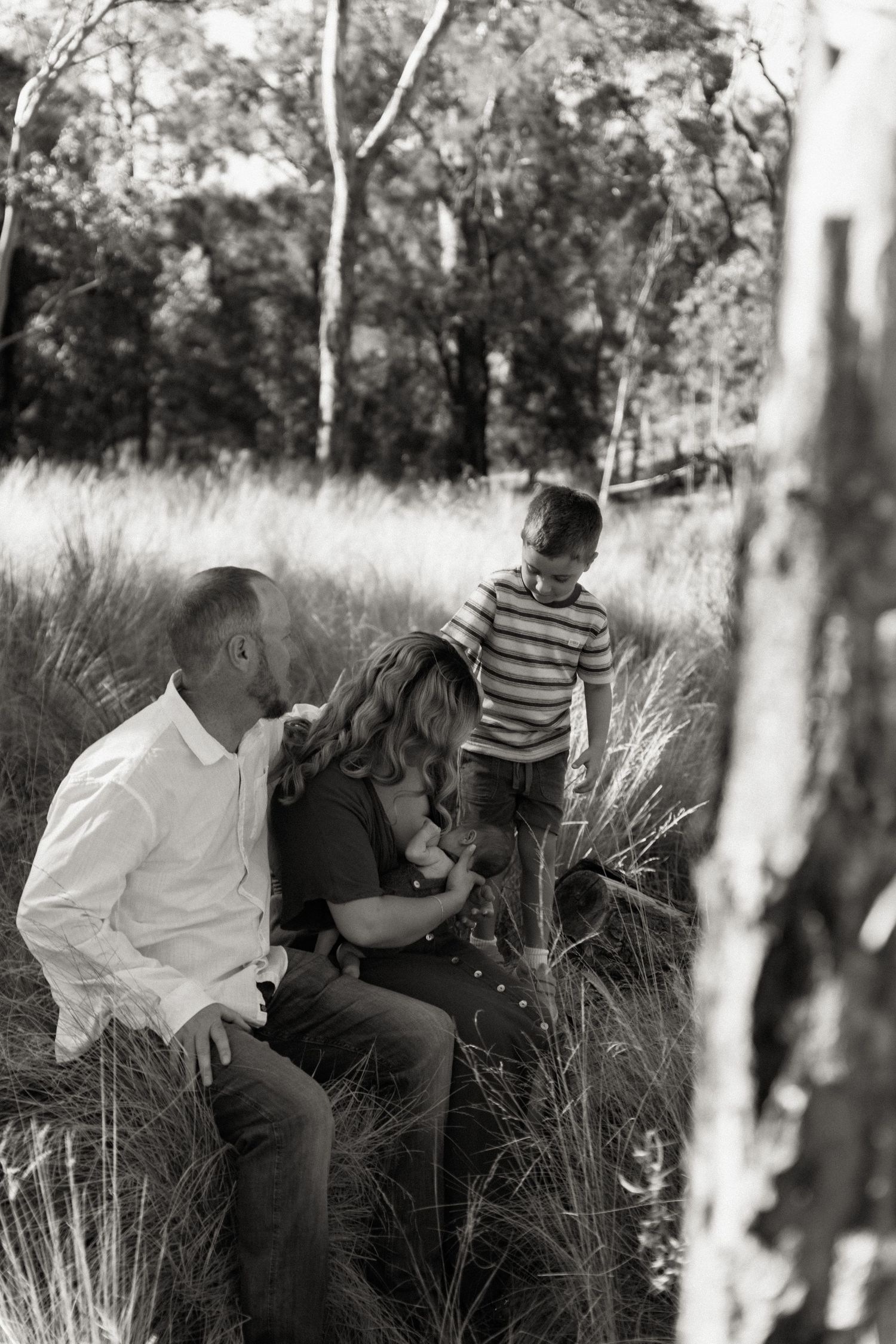 Black and white photo of a family with two children sitting together in a grassy outdoor setting.