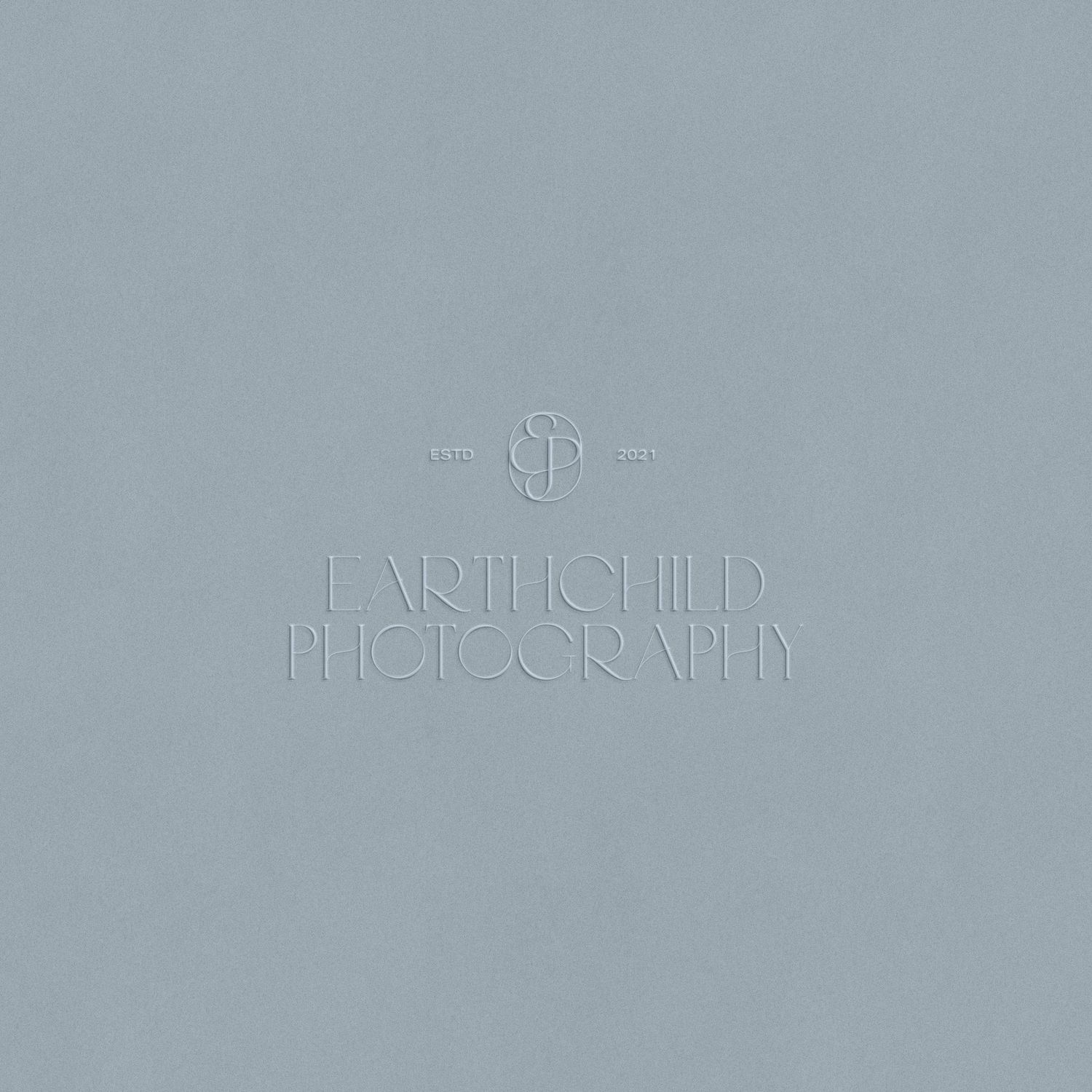 Earthchild Photography logo embossed on a muted blue-gray background with subtle monogram design.