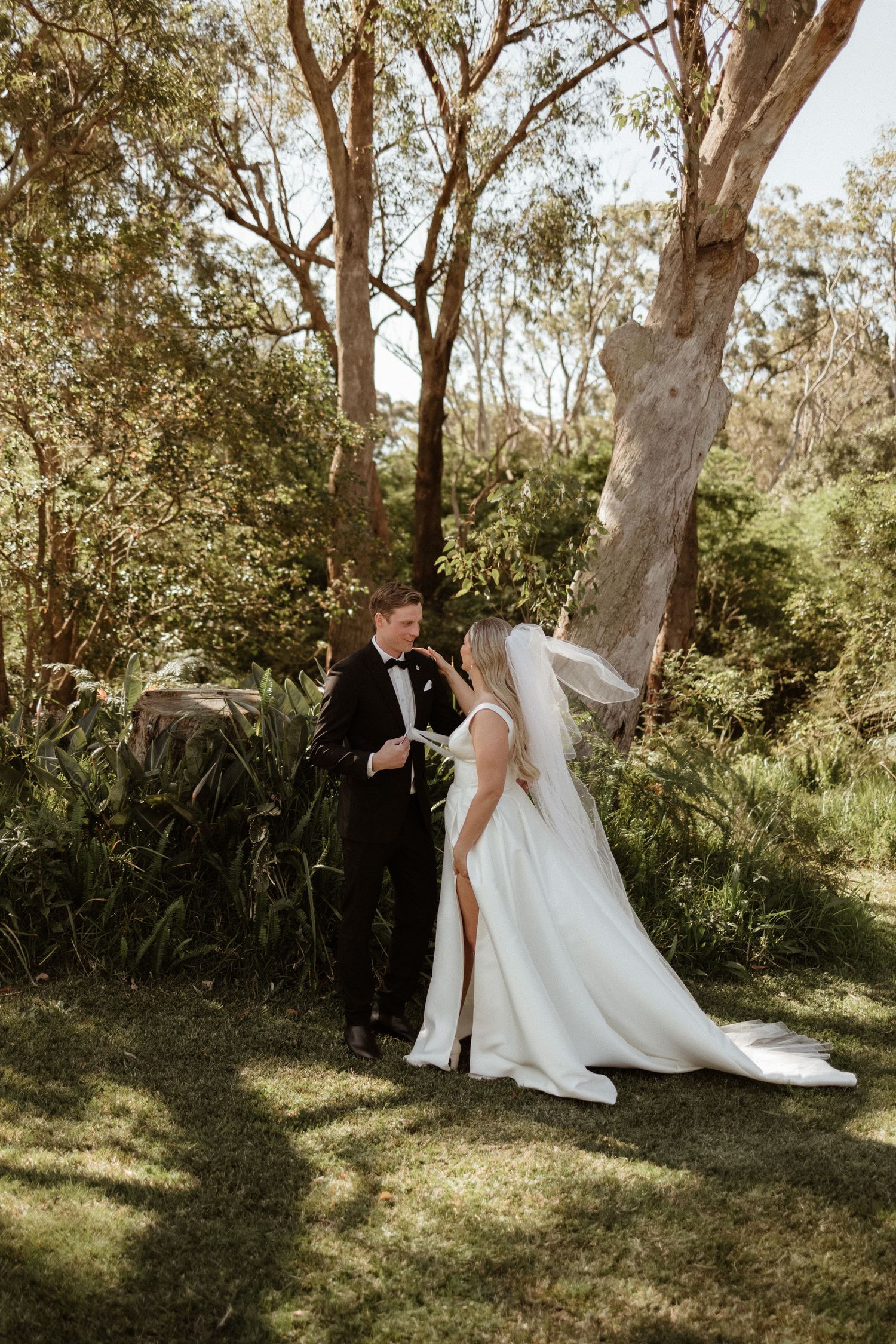 Bride and groom sharing a tender moment in a lush green garden setting on their wedding day.