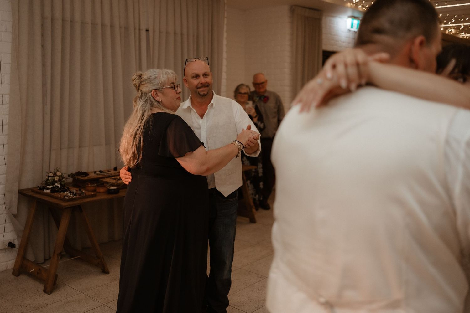Guests share joyful dances together at an elegant indoor wedding reception celebration.