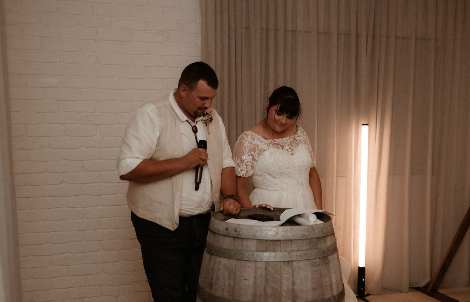 Bride and groom reading vows together over a rustic barrel altar during intimate wedding ceremony.