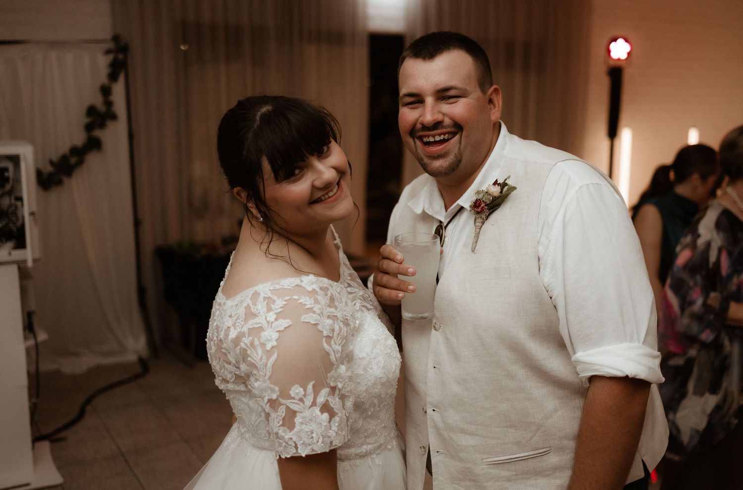 Happy bride and groom laugh together sharing a joyful moment at their wedding reception.