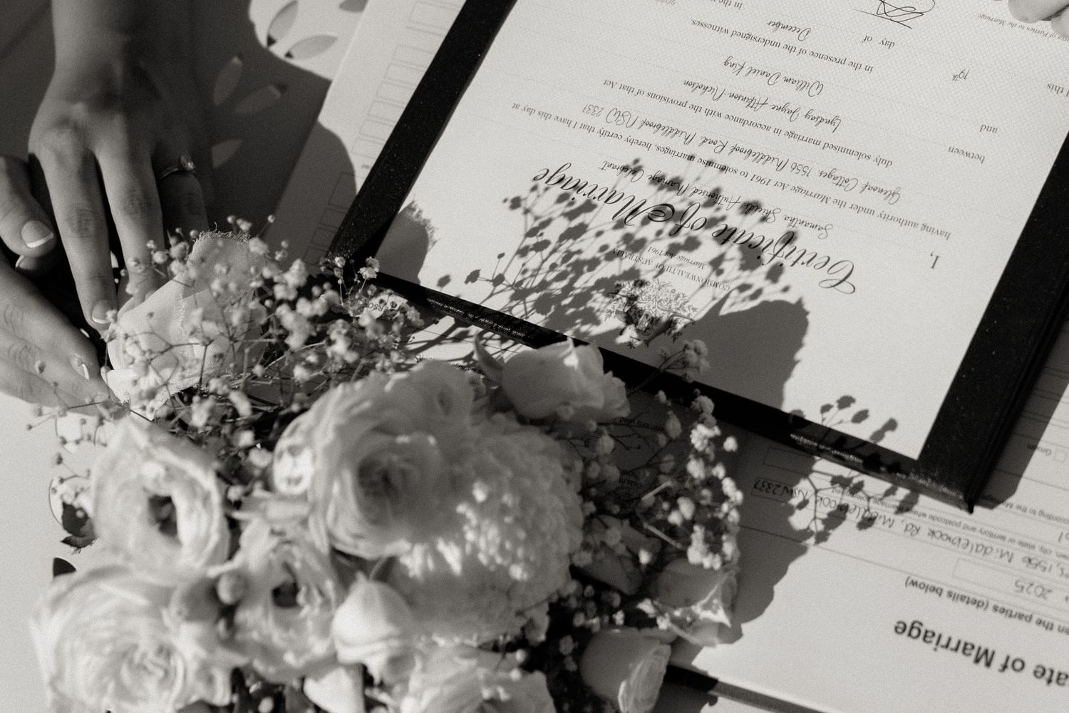 Black and white photo of a wedding bouquet with roses beside a Certificate of Marriage document.