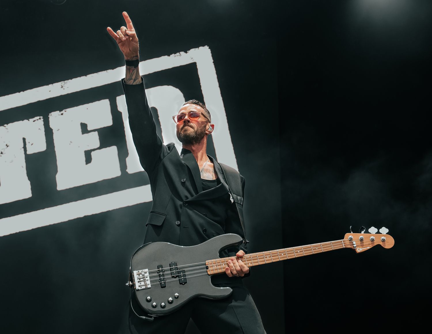 Musician playing bass guitar on stage during rock concert.