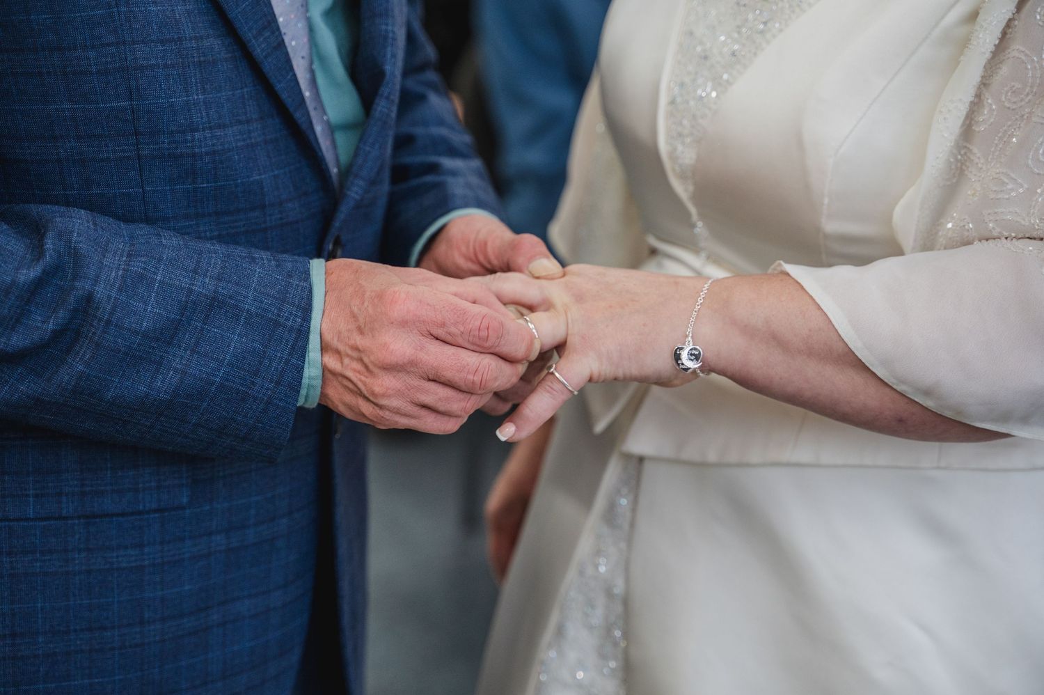 Close-up view of hands exchanging wedding rings during a traditional marriage ceremony.