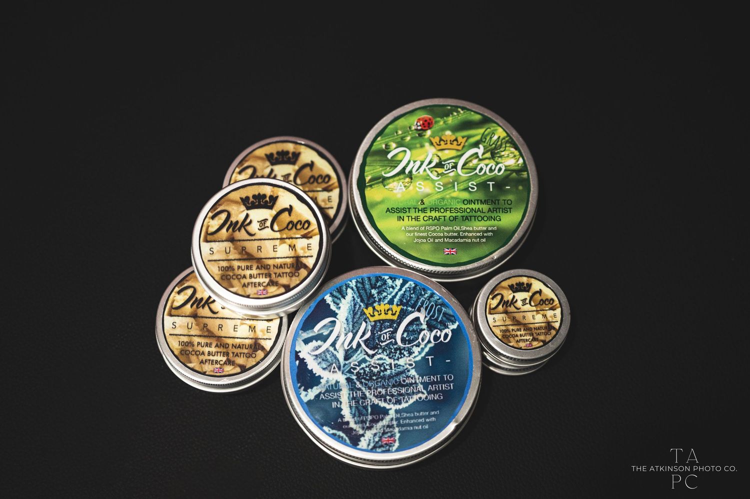 Collection of artisanal grooming product tins arranged on black background.